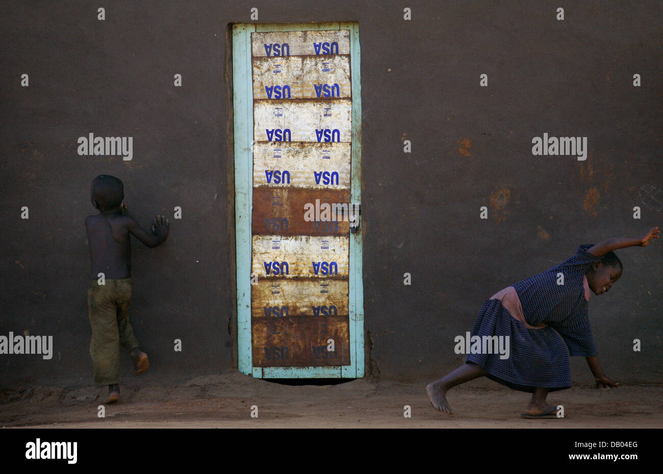 Children Play Near A Rusty Door Made Of Tin Cans From The Us