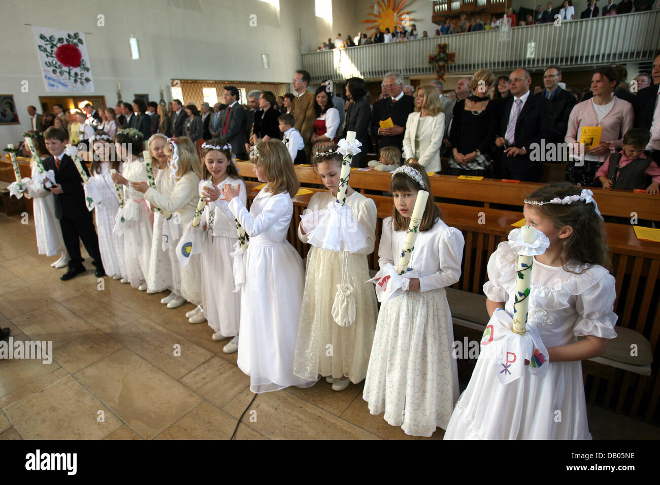 Girls in traditional dresses hold candles during the First Communion  ceremony at Catholic Saint Peter and Paul church in Baierbrunn, Germany, 15  April 2007. Photo: Stephan Jansen Stock Photo - Alamy