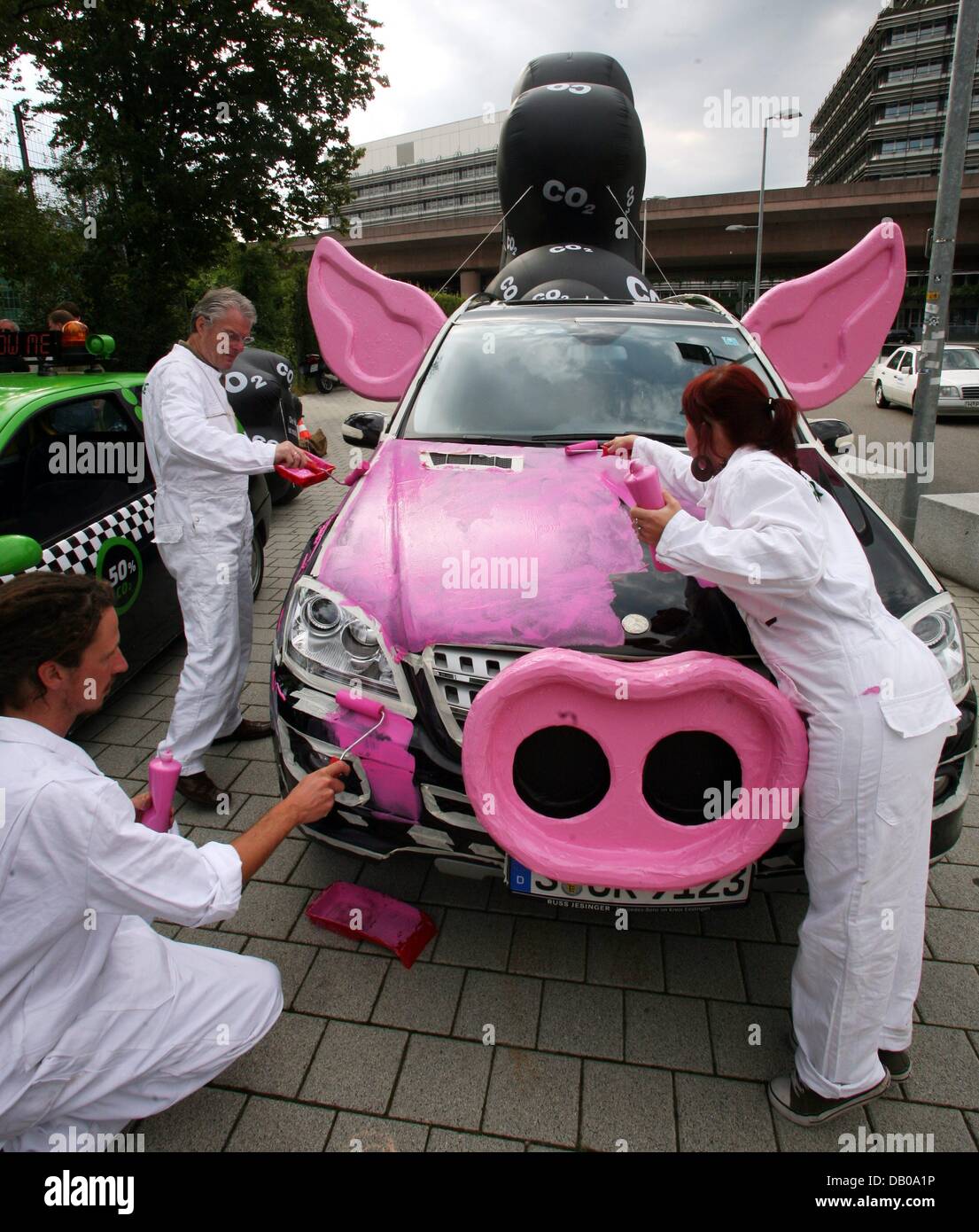 Members of environmental protection organisation 'Greenpeace' prepare a protest campaign against climate-damaging policies of automobile manufacturer DaimlerChrysler in front of the Mercedes-Benz museum in Stuttgart, Germany, 25 July 2007. For this purpose the campaigners paint two Mercedes cars in pink and decorate them with snouts and ears to symbolise pigs. Giant balloons stand  Stock Photo