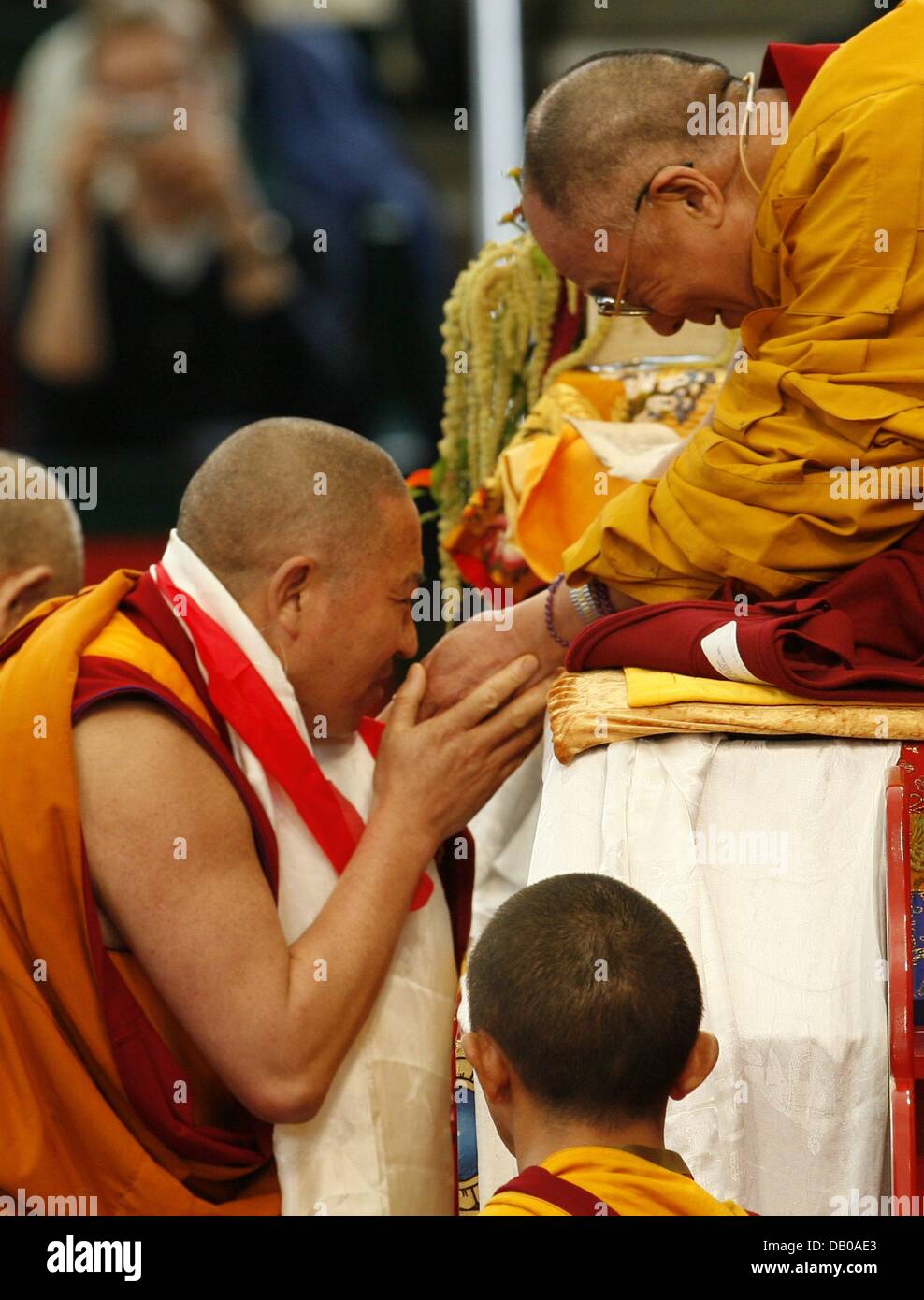 A monk gets in touch with the Dalai Lama (R) on his throne in Hamburg, Germany, 27 July 2007. The 72-year-old Nobel Peace Prize Laureate ended his ten-day visit to Hamburg with a blessing and continues to Freiburg, Germany on 28 July to lecture on the theme Economy and Spirituality. Photo: Sebastian Widmann Stock Photo