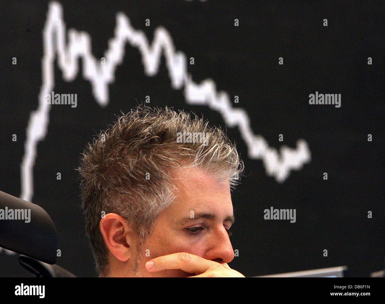 A stockbroker sits in front of a display panel showing the curve of the DAX at the Frankfurt Stock Exchange, Germany, 17 August 2007. Following the unexpected reduction of the discount rate in the US the downward tendency of the  DAX was halted and reversed. Meanwhile the Dax had gone up by 1.71 point up to 7394.36. Photo: Boris Roessler Stock Photo