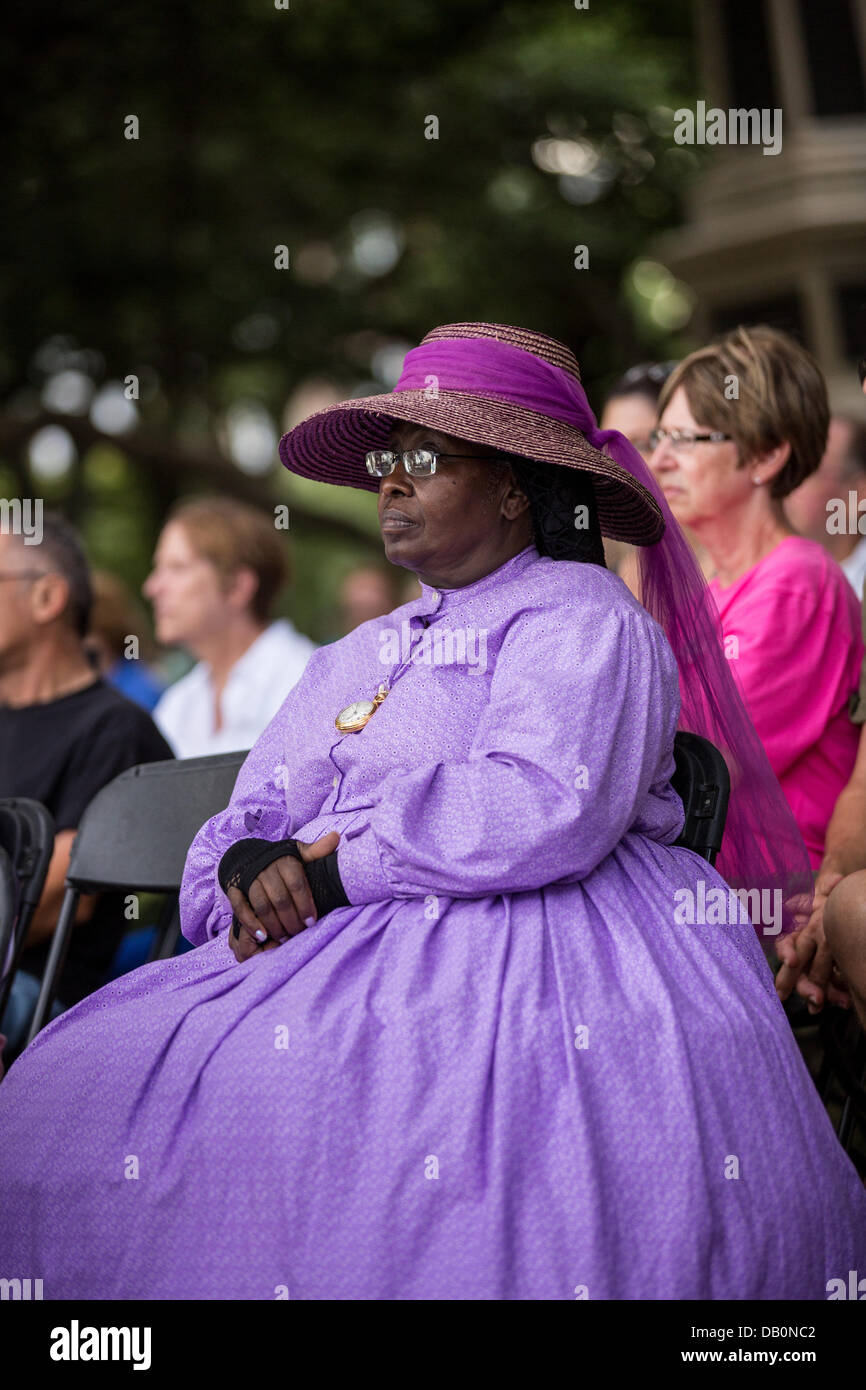 A woman dressed in Civil War costume listens during a ceremony unveiling a memorial honoring the 54th on the 150th anniversary of the assault on Battery Wagner July 21, 2013 in Charleston, SC. The battle memorialized in the movie 'Glory' took place in Charleston and was the first major battle of an all black regiment. Stock Photo