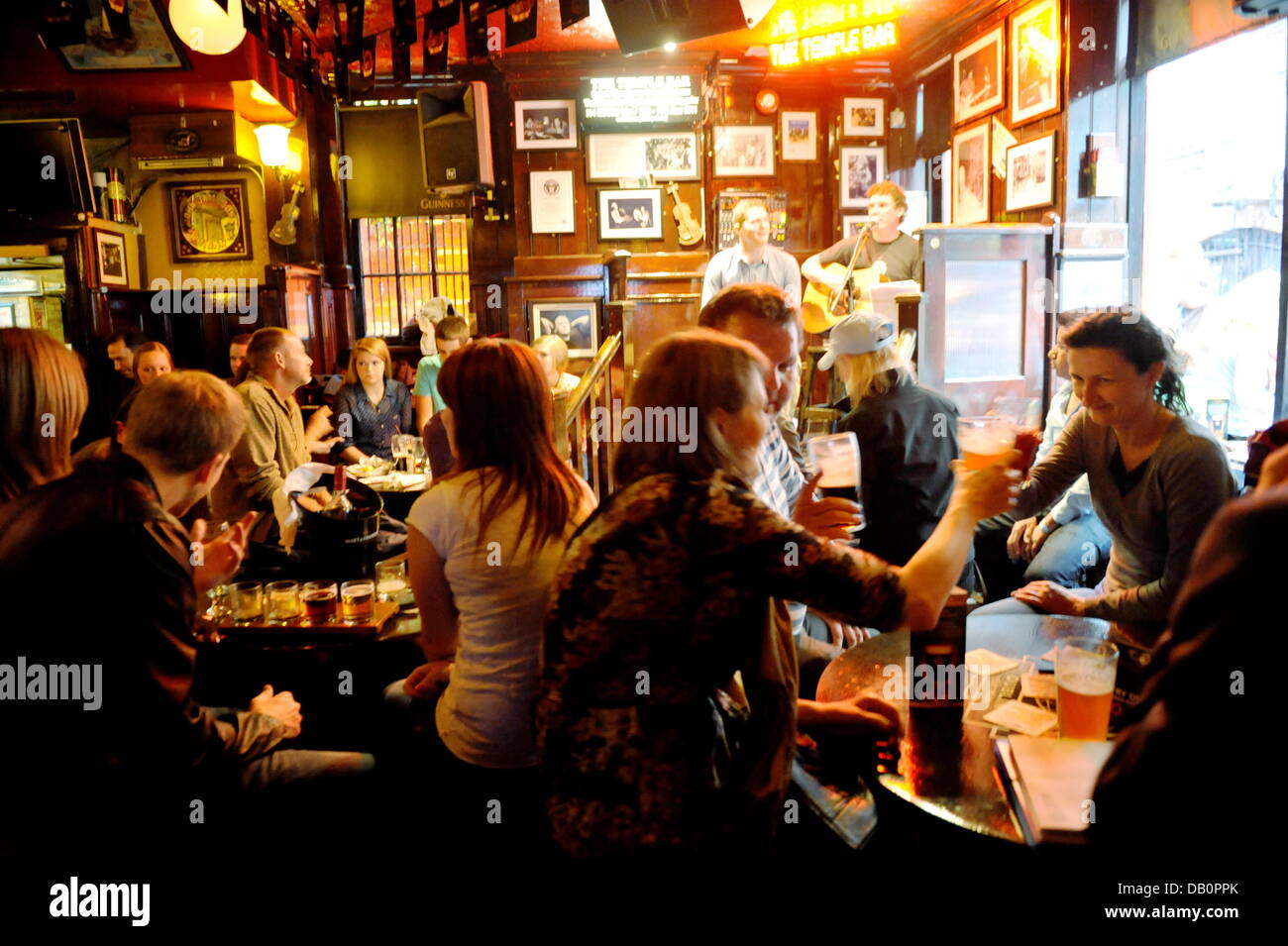 Visitors of the Temple Bar-Quarter in Dublin take a beer in iinside the pub 'Temple Bar, on June 26, 2013. Musicians entertain the guests with irish Folk Music. Stock Photo