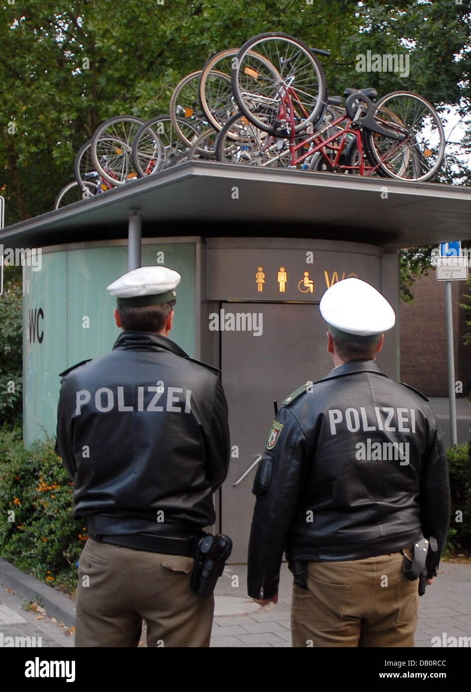 Policemen take a look at several bikes arranged on a public toilet in Muenster, Germany, 19 September 2007. The art exhibition 'sculpture projects' seemed to have inspired someone's creativity. It is not an authorised work of the exhibition. Photo: Polizei Muenster Stock Photo