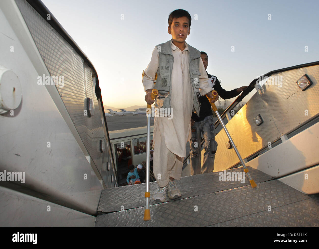 An Afghan boy on crutches goes on board a plane departing for Hamburg (Germany) from Kabul