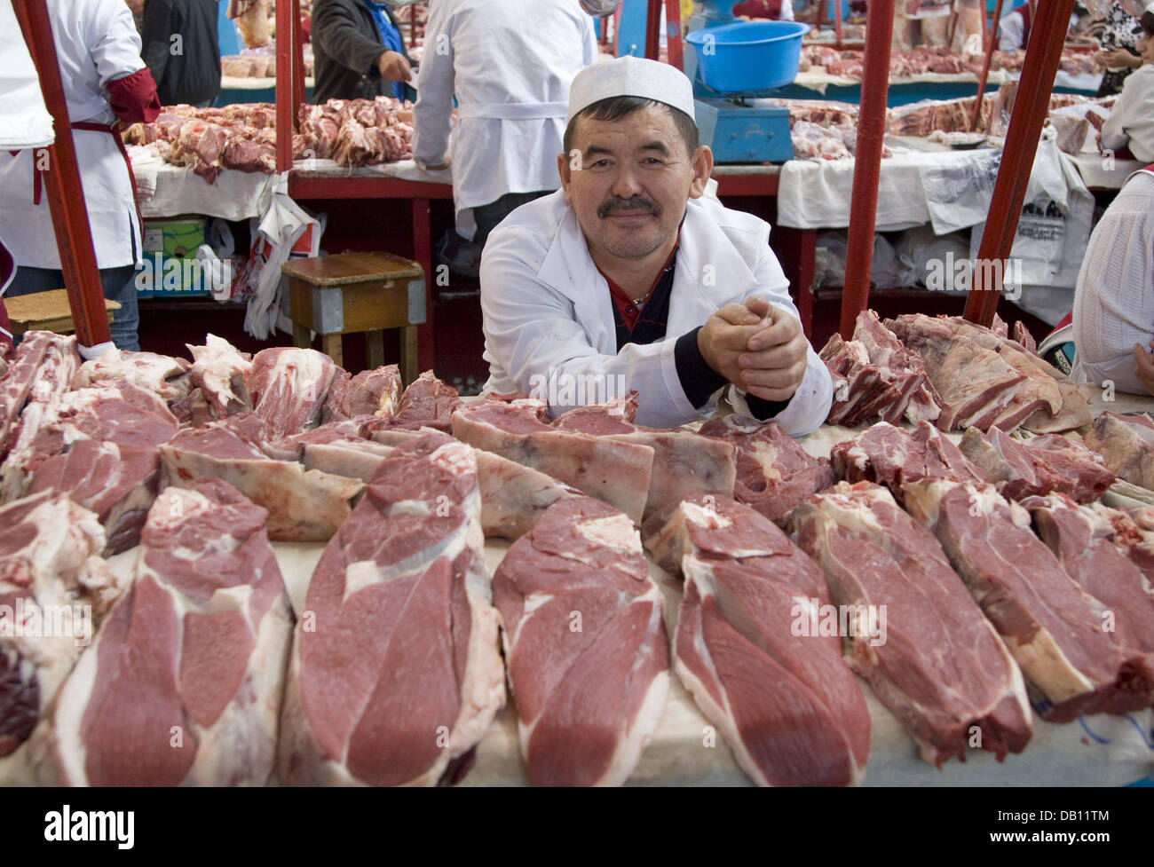 A meat vendor waits for customers behind his stall at a market hall in