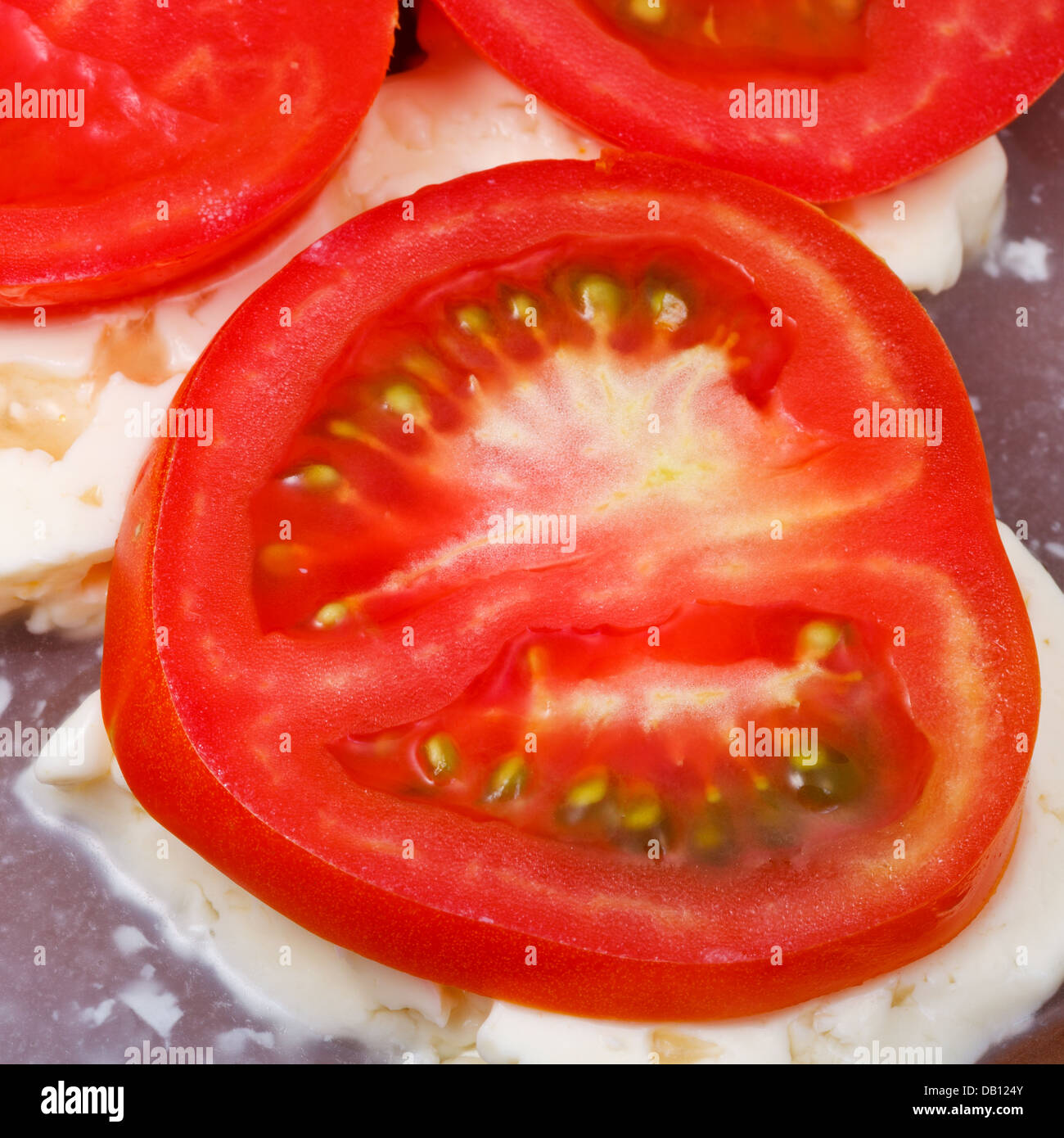 sliced tomatoes and brined cheese on ceramic plate close up Stock Photo