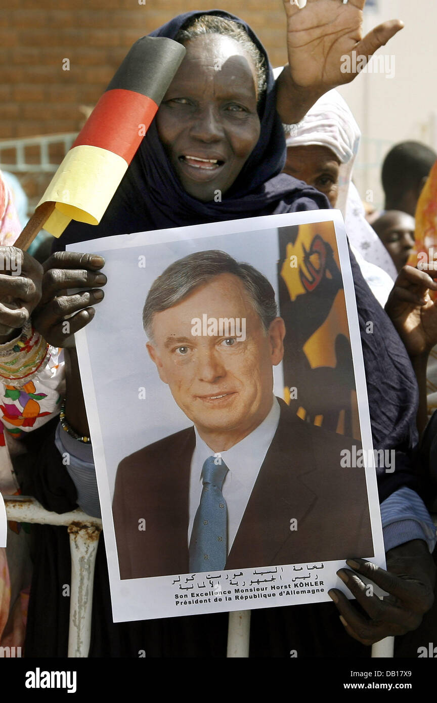 A Mauritanian woman holds a portrait and a German flag to welcome German President Horst Koehler in Nouakchott, Mauritania, 14 November 2007. Koehler and his wife Eva are on an official visit in North Africa and will visit Algeria, Mauritania and Malta. Photo: WOLFGANG KUMM Stock Photo
