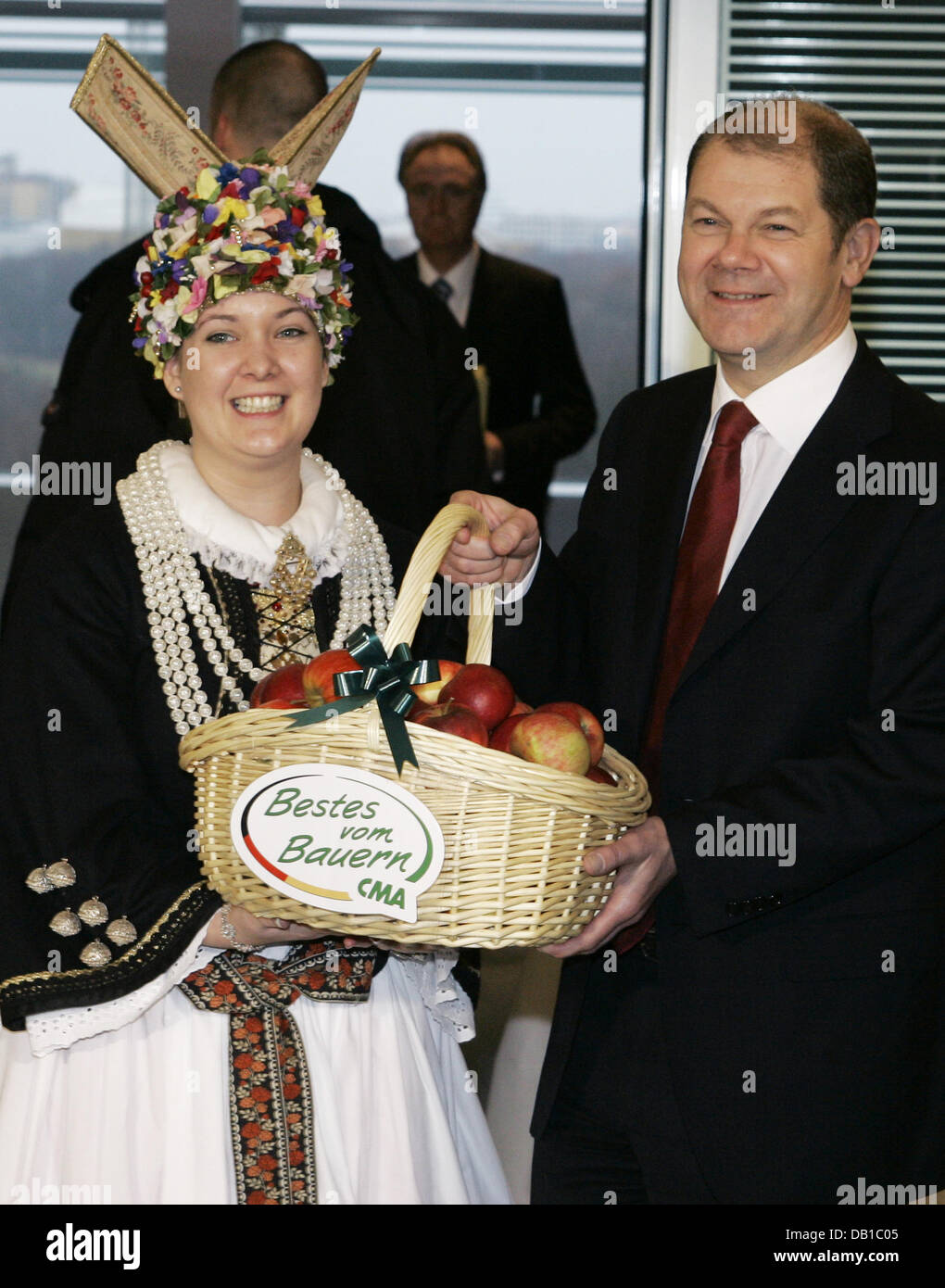 Labour Minister Olaf Scholz holds a basket he was presented with by the  Altes Land Blossom Queen Kathrin Feindt (L) prior to a cabinet meeting at  the Chancellery in Berlin, Wednesday, 5