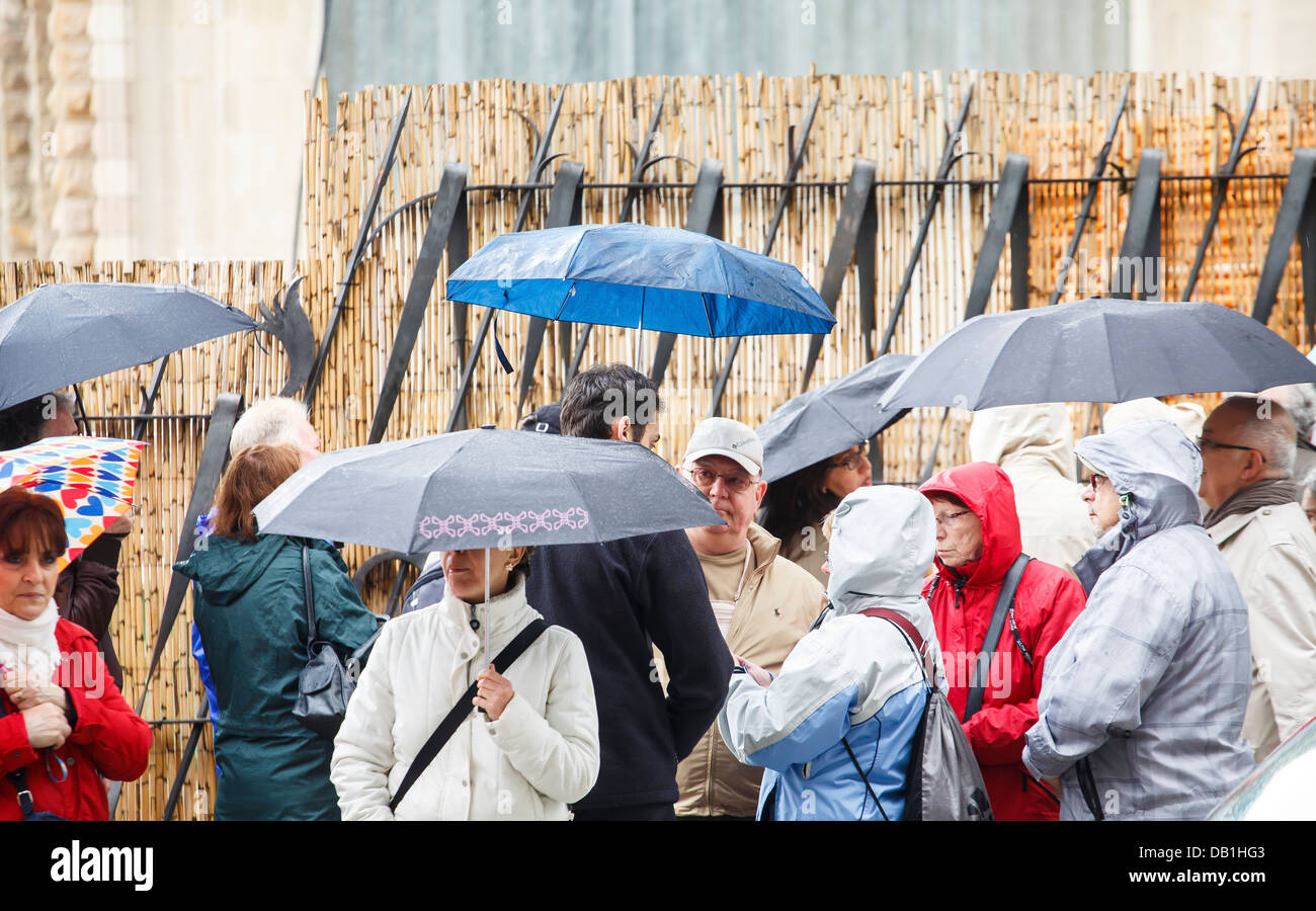 Many people standing on a city street with umbrellas wearing rain gear Stock Photo