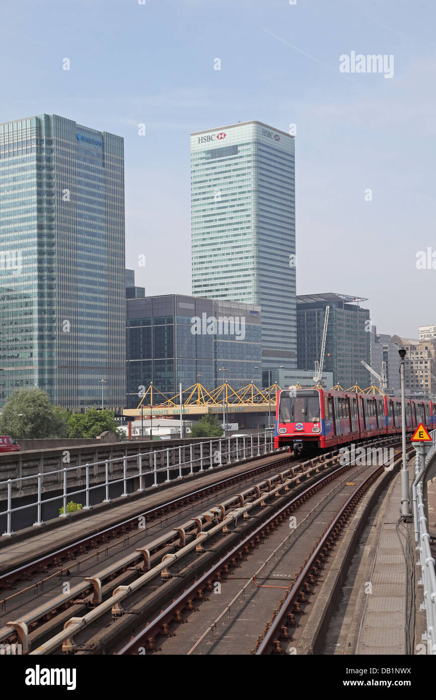 A London Docklands Light Railway train leaves Blackwall station. Canary Wharf business district in the background Stock Photo