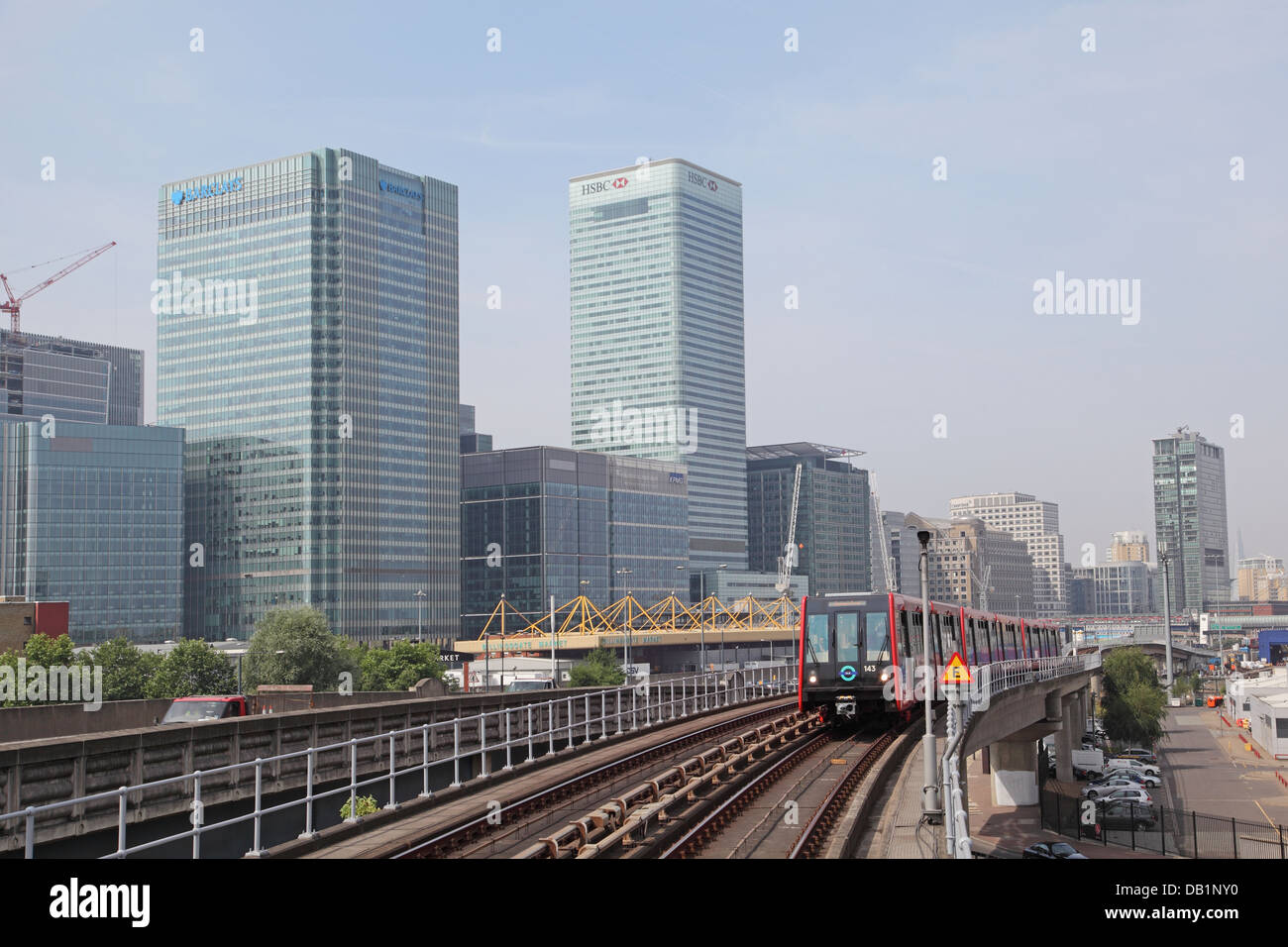 A London Docklands Light Railway train approaches Blackwall  station. Canary Wharf business district in the background Stock Photo