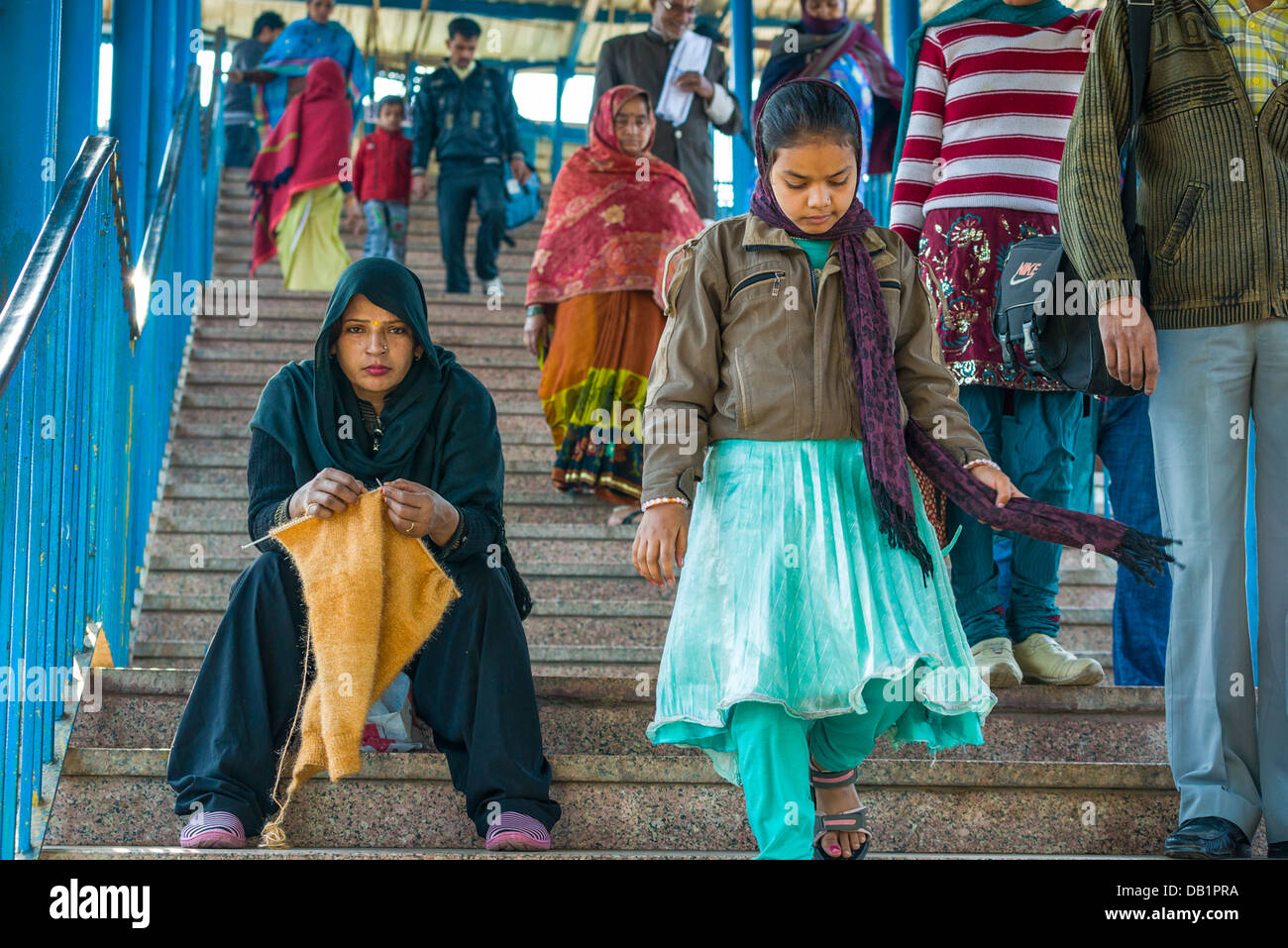 Indian woman knitting on the steps at New Delhi Railway Station, New Delhi, India Stock Photo
