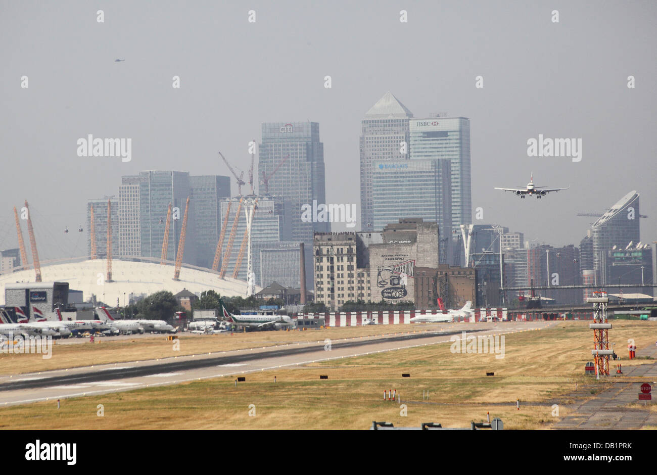 A passenger jet lands at London City Airport. Canary Wharf and the Millennium Dome in background Stock Photo