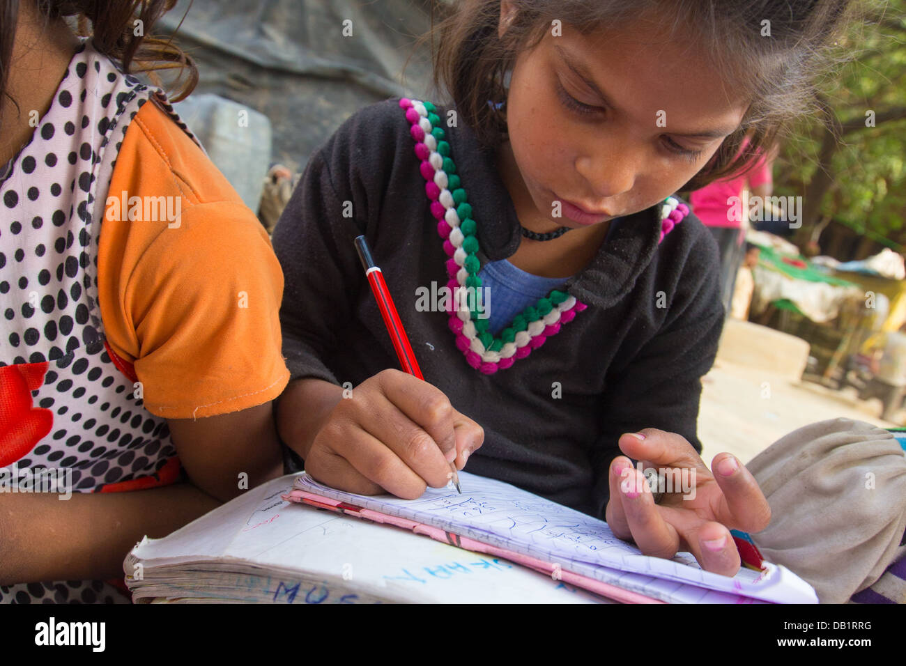 Young girl doing math in a notebook in a slum in New Delhi, India Stock Photo