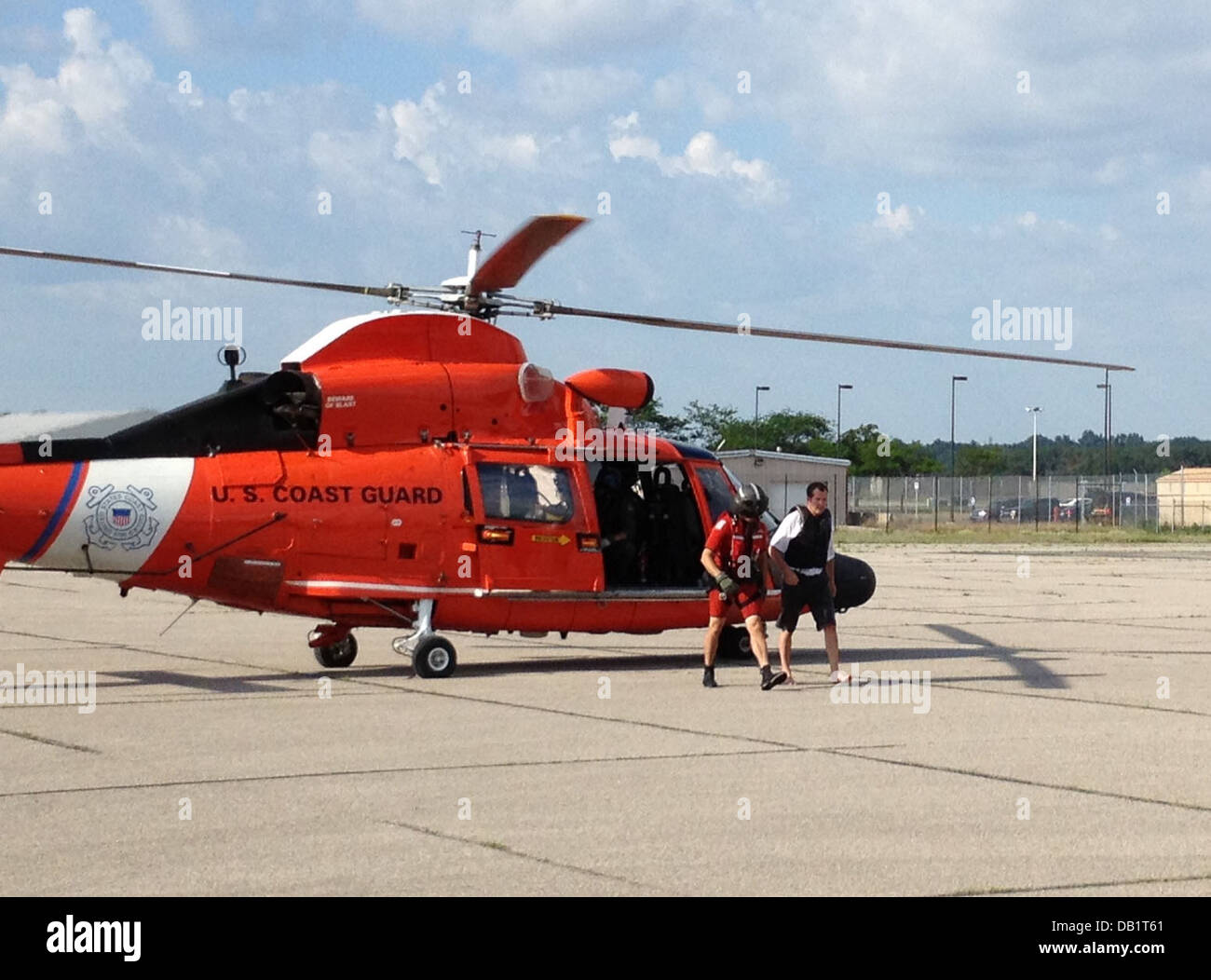 Petty Officer 2nd Class Erik Lieb, a Coast Guard rescue swimmer assigned to Air Station Traverse City, escorts a kayaker that was rescued by the MH-65 Dolphin helicopter crew from the East Arm of Grand Traverse Bay, July 19, 2013. The aircrew spotted the Stock Photo