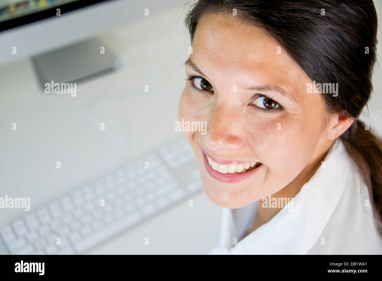 woman sitting at working desk is smiling Stock Photo