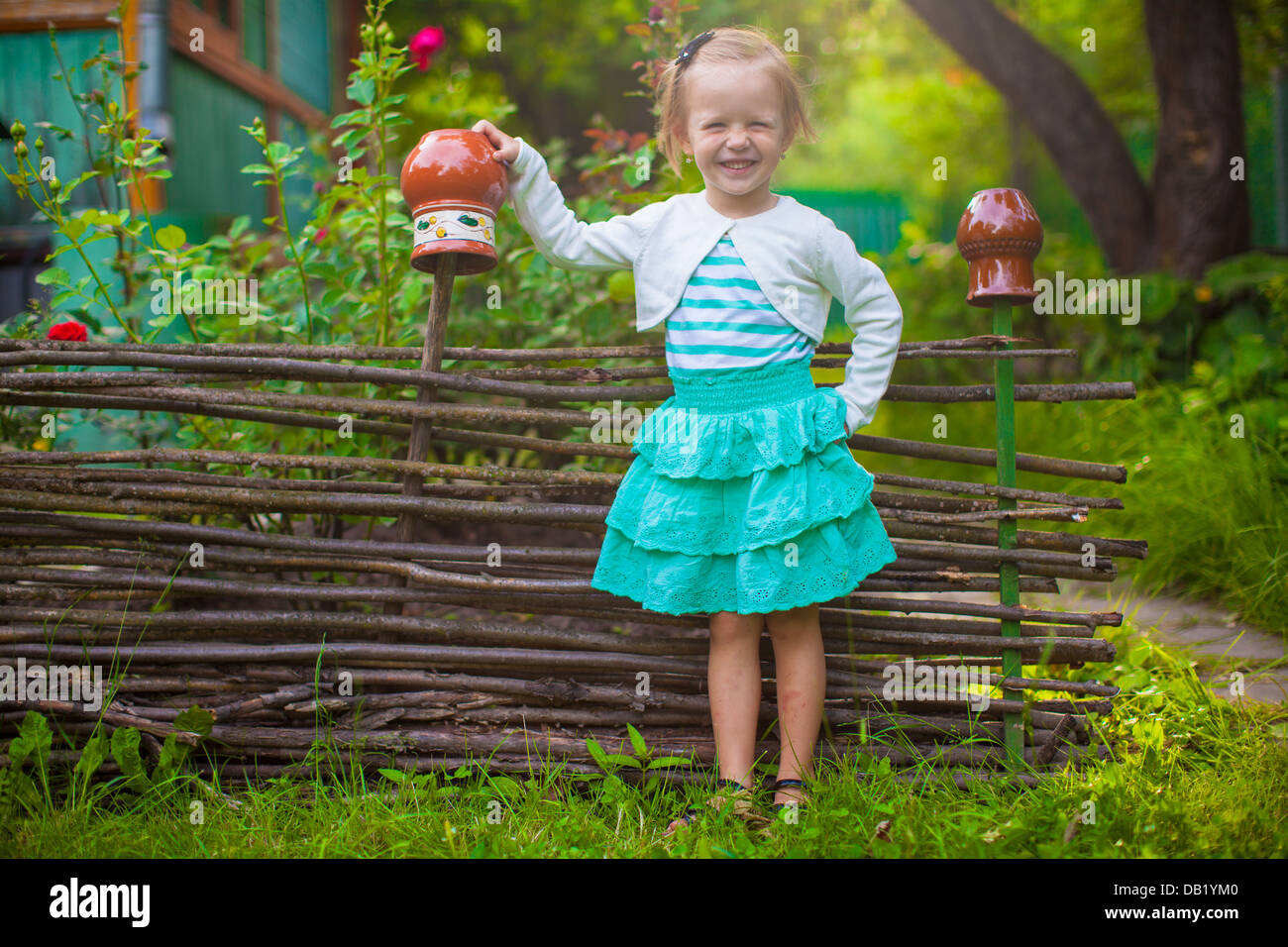 Adorable little girl standing near vintage wooden rural fence and ...