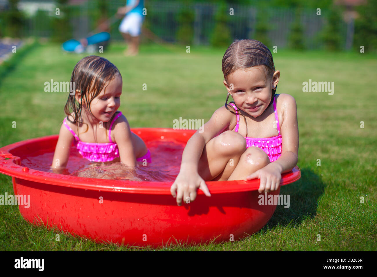 Two Cute Little Sisters Frolicing And Splashing In Their Yard In Small