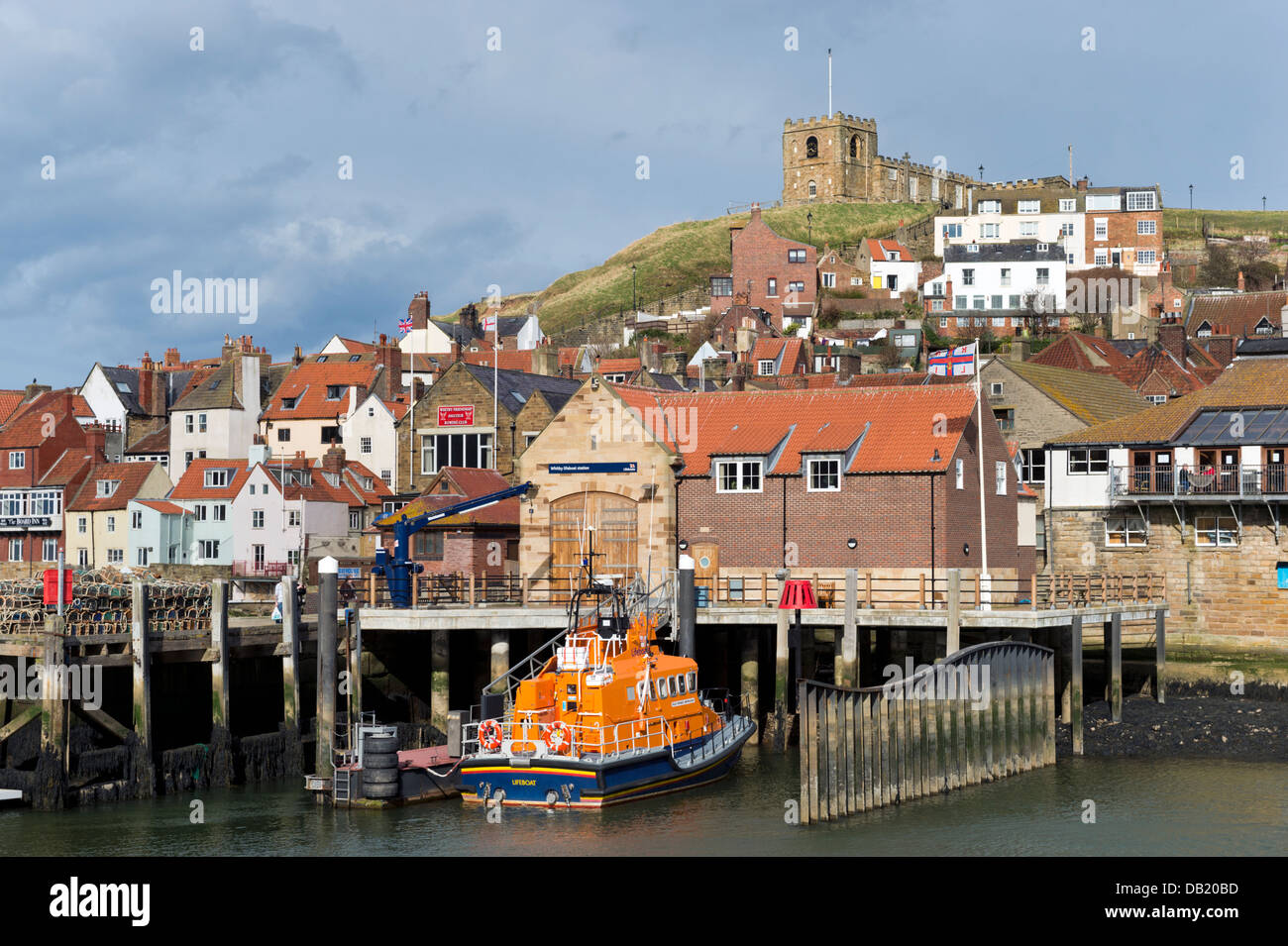 The harbour, with the Lifeboat moored at the quay and St Mary's Church on the cliffs above, Whitby, Yorkshire, UK Stock Photo