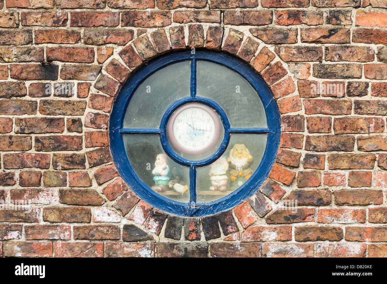 Round window with clock in centre and garden gnomes looking out of ...