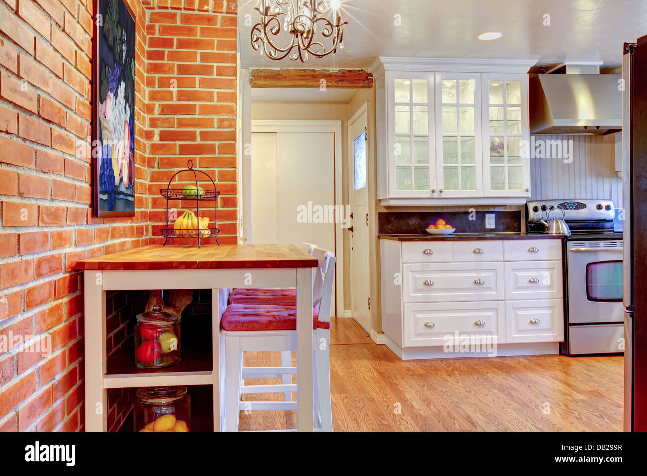 White kitchen with brick wall, hardwood and stainless steal stove. Stock Photo