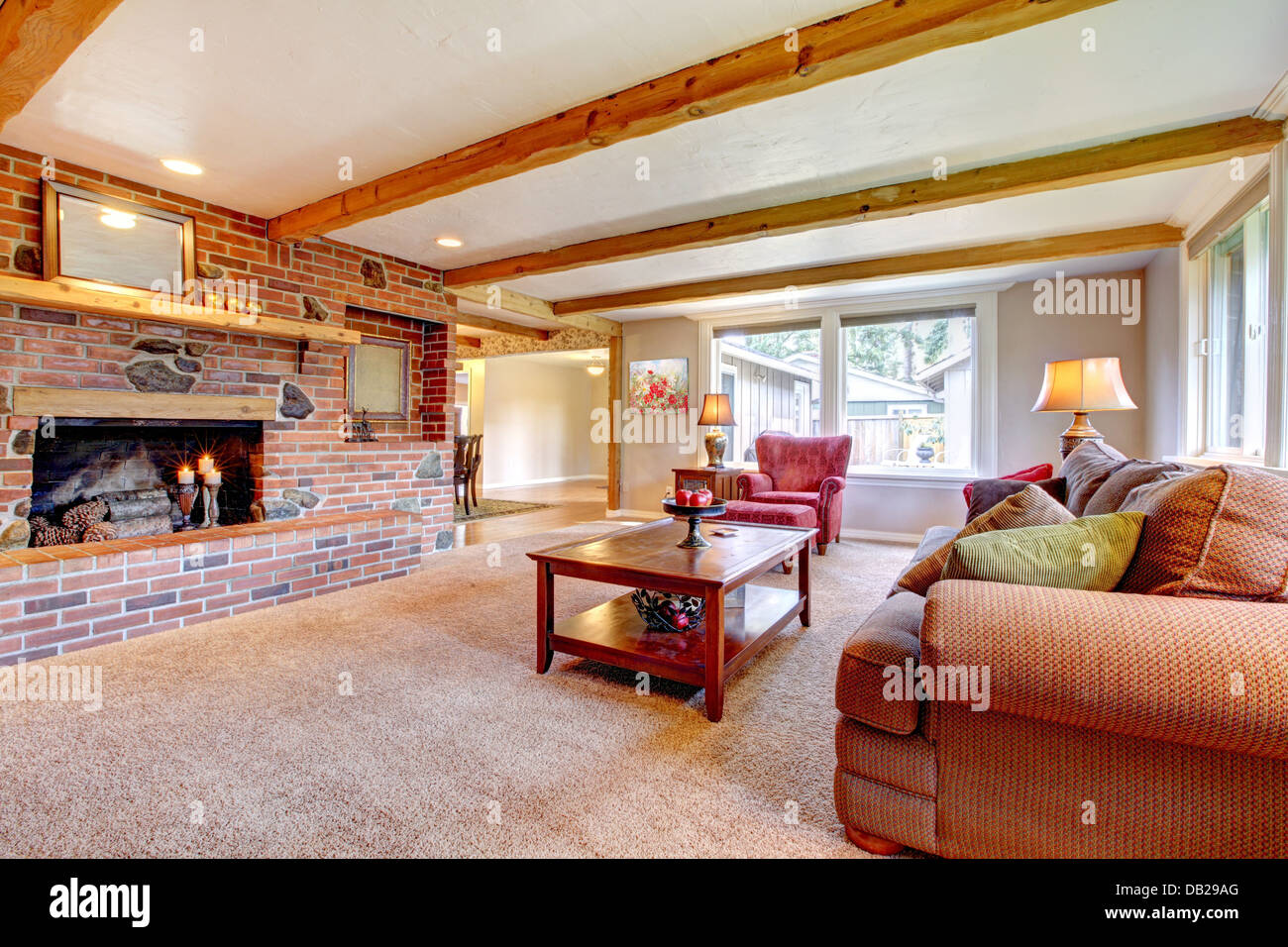 Living room interior with brick fireplace, wood beams and red. Stock Photo