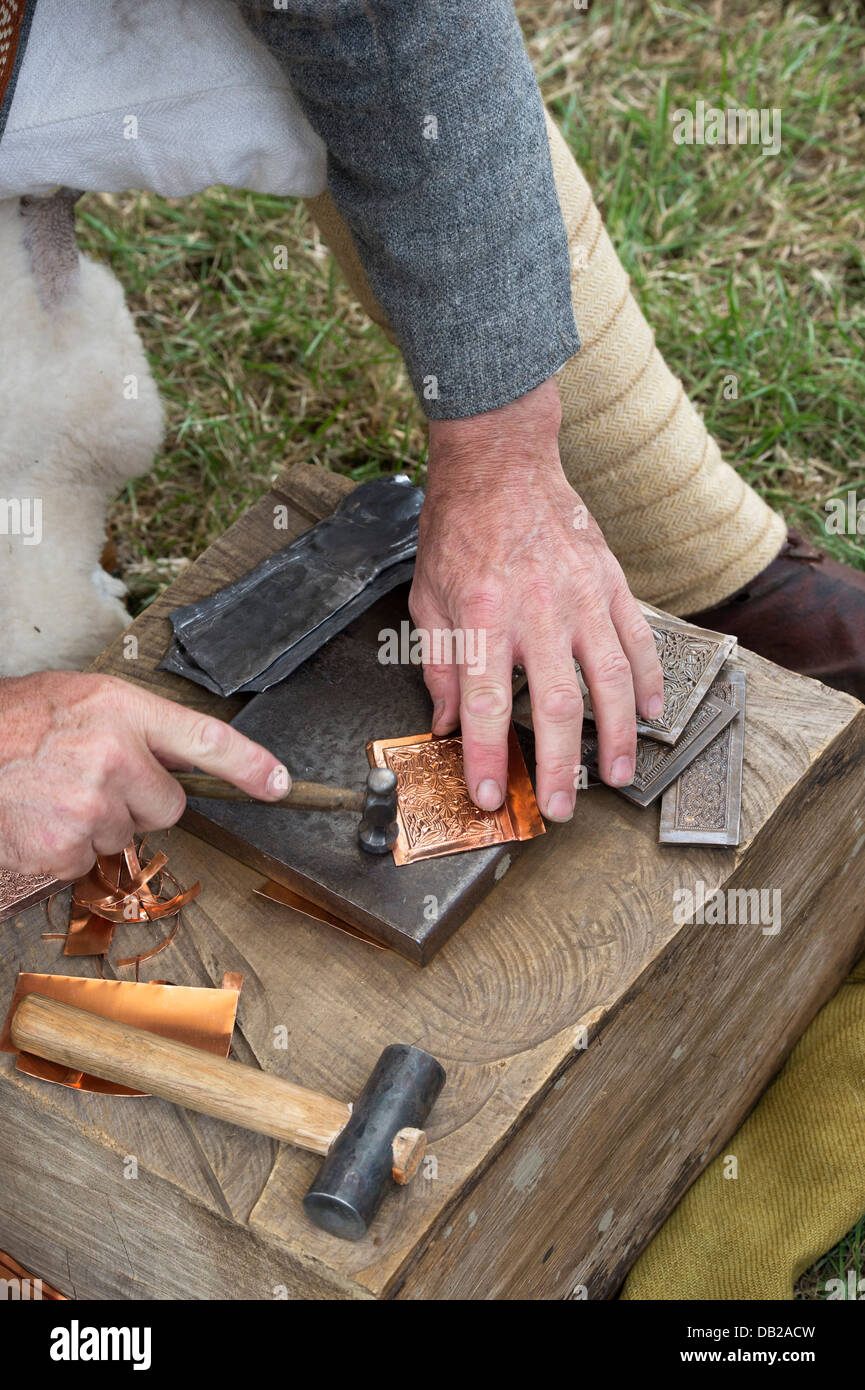 Skilled craftsman making replica Anglo Saxon designs onto copper sheet at a historical re enactment Stock Photo