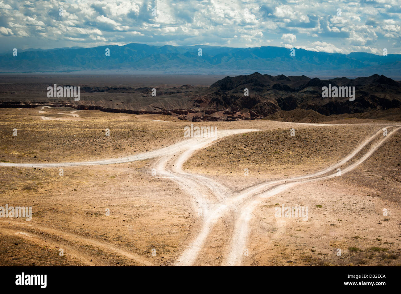 Empty rural road going through prairie under cloudy sky in Charyn canyon. State National Paleontology Park in Kazakhstan Stock Photo