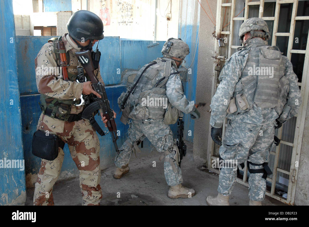 An American-Iraqi joint patrol opens a  locked door during a search for hidden weapons at the race-course in Bagdad, Iraq, March 2007. The US soldiers belong to the 'Apache' 6th Division. Company 1st Battalion 23rd Infantry, the Iraqui soldier (L) belongs to the 6th Division. Photo: Carl Schulze Stock Photo