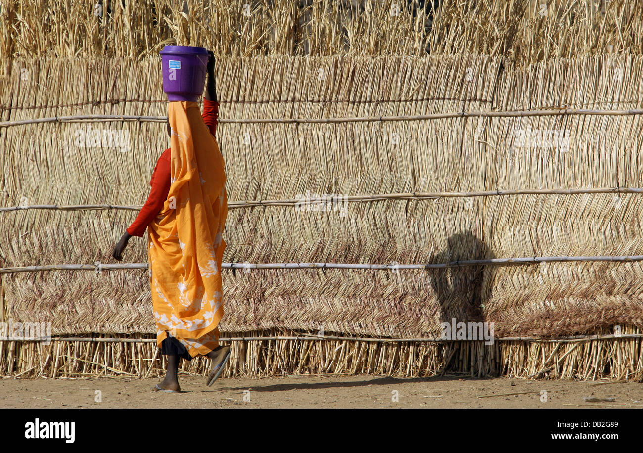 A Sudanese woman carries a water bucket on her head in Mukjar in Western Dafur, Sudan, 09 December 2007. Photo: Peter Steffen Stock Photo