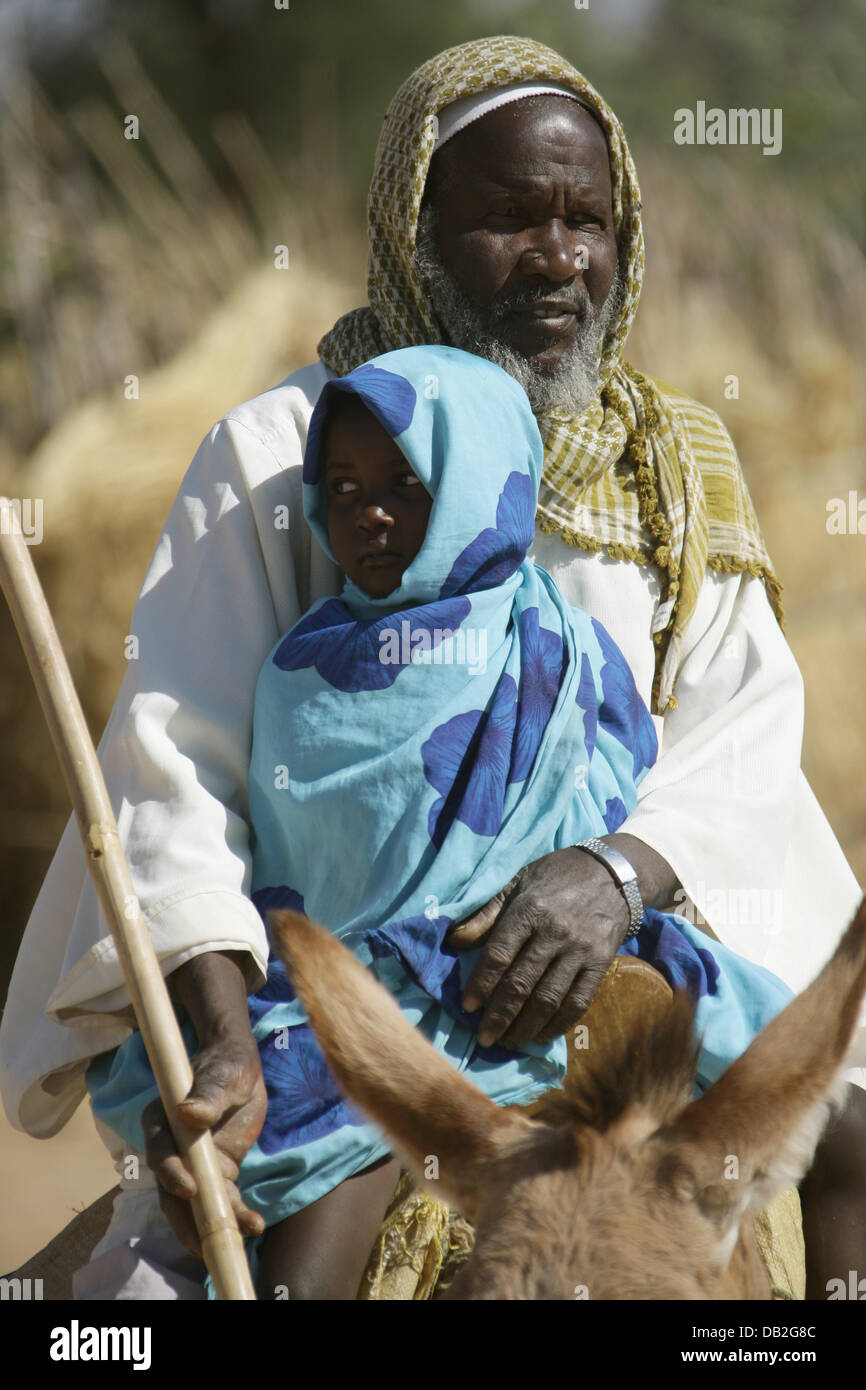 A Sudanes farmer rides a long distance with his sick child in order for it to get medical treatment in the village of Buru in Western Dafur, Sudan, 11 December 2007. Doctors drive all the way from Mukjar to villages which are up to 100 kilometres away, in order to treat sick persons. The health post is operated by the German Red Cross (DRK) and the Sudanese Red Crescent Movement. P Stock Photo