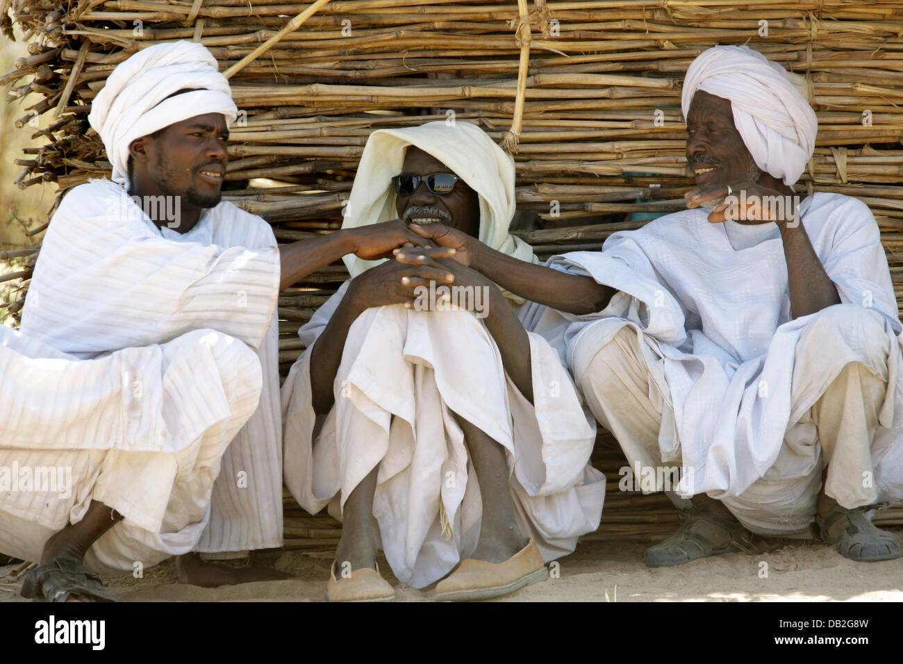 Three Sudanese men chat leaning against a hut in the village of Buru in Western Dafur, Sudan, 11 December 2007. Photo: Peter Steffen Stock Photo
