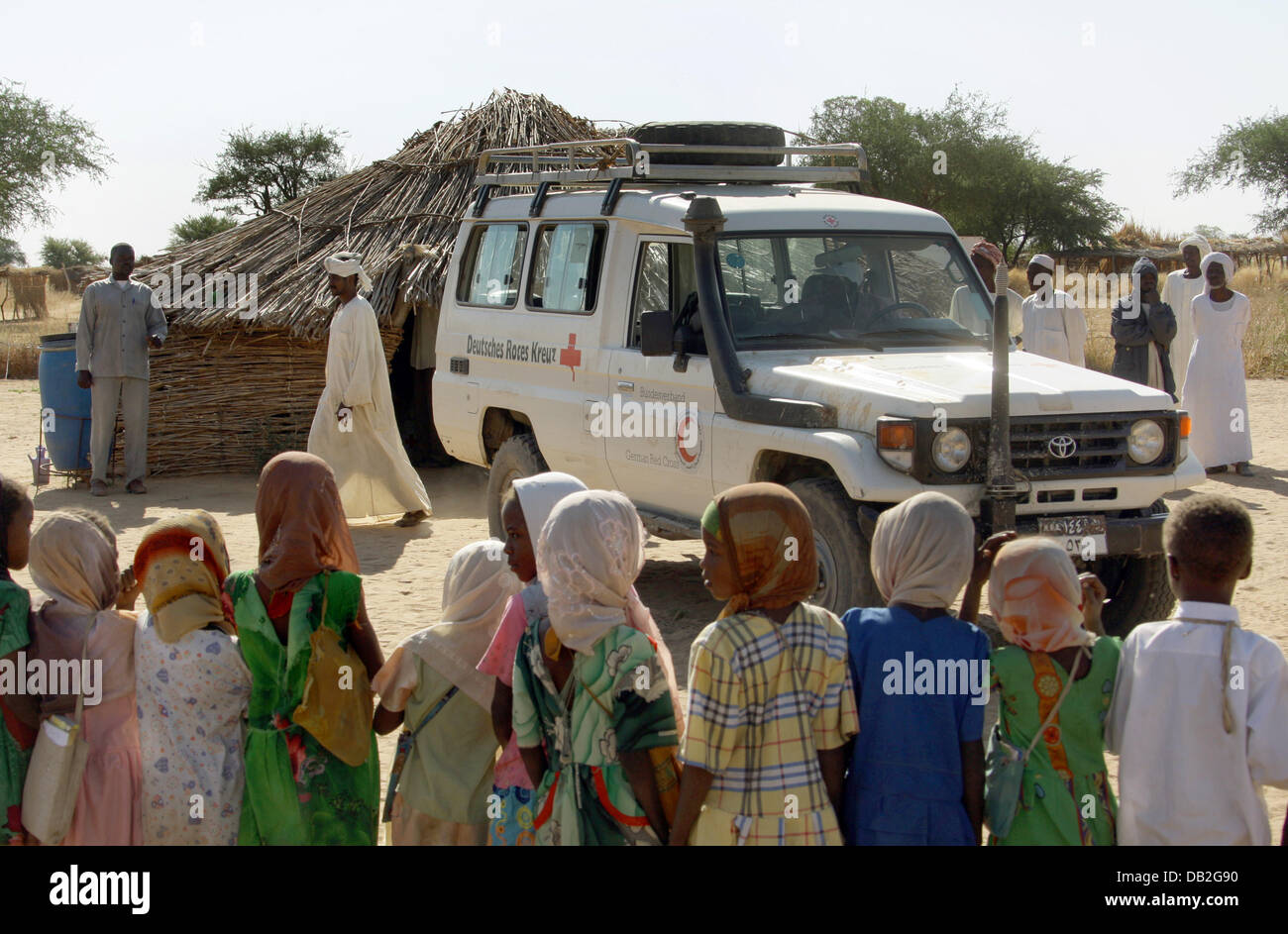 Villagers, among them many children, gather to welcome a mobile health post jeep in the village of Buru in Western Dafur, Sudan, 11 December 2007. Doctors drive all the way from Mukjar to villages which are up to 100 kilometres away, in order to treat sick persons. The health post is operated by the German Red Cross (DRK) and the Sudanese Red Crescent Movement. Photo: Peter Steffen Stock Photo