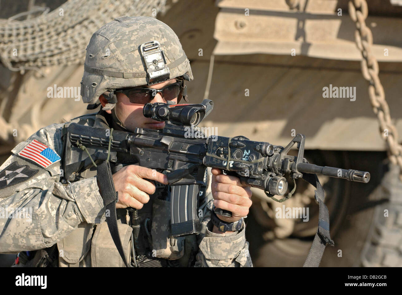An infantryman of the 3rd US Stryker Brigade Combat Team aims with this M4A1 carbine during a search operation in Bagdad, Iraq, March 2007. The remote controlled Explosive Ordnance Disposal Roboter is used to examine potential improvised explosive device (IED). Photo: Carl Schulze Stock Photo