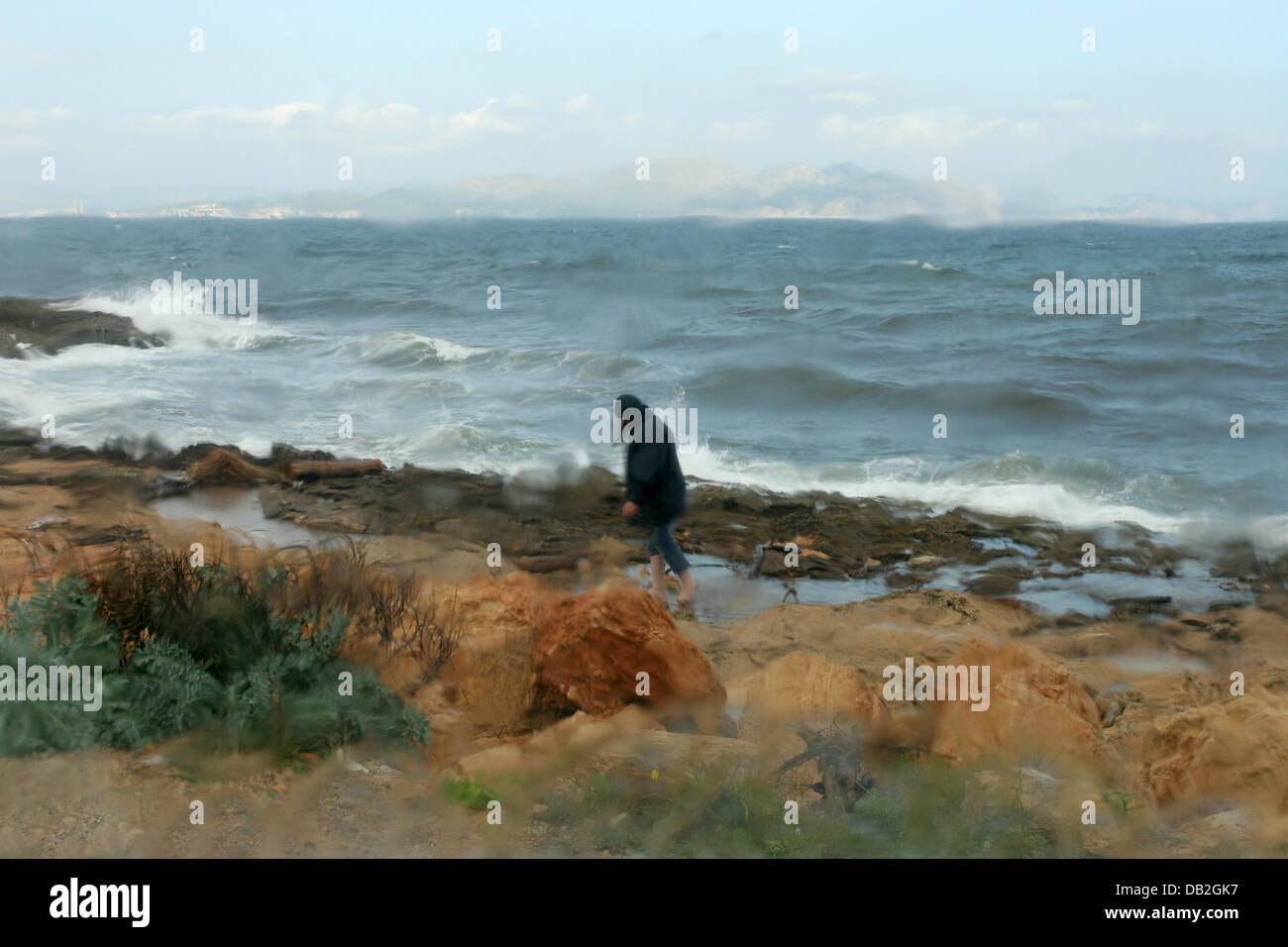 Despite stormy weather a person takes a walk at the agitated bay of Alcudia on Majorca, Spain, 18 October 2007. Photo: Heiko Wolfraum Stock Photo