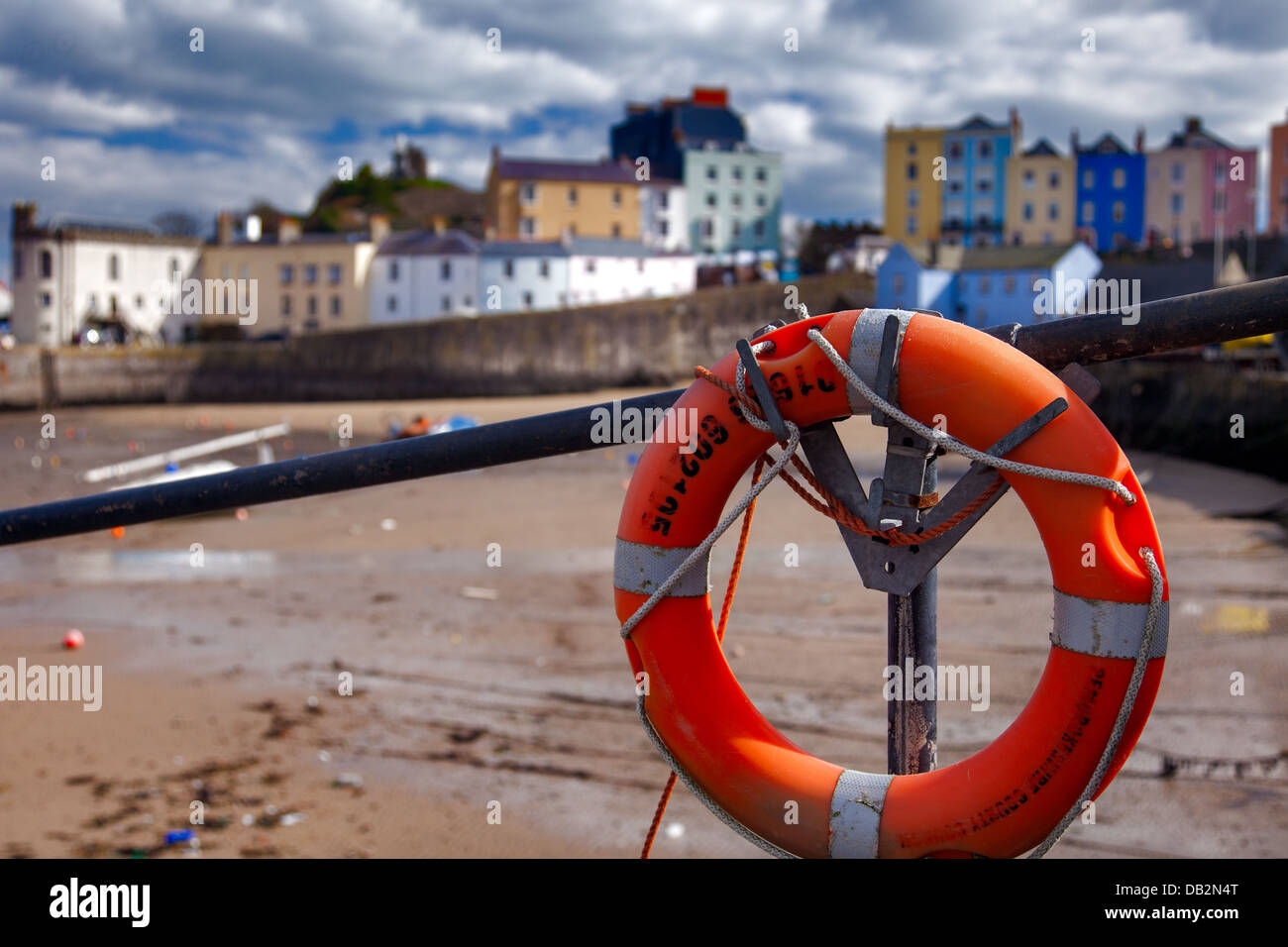 A view of the colourful houses surrounding the harbour at Tenby, South Wales showing an orange life saving ring in foreground. Stock Photo