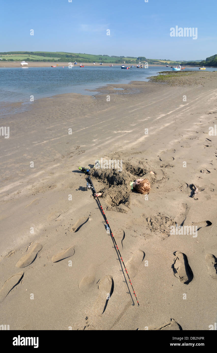 young boy buried in sand with fishing pole poppit sands st dogmaels ...