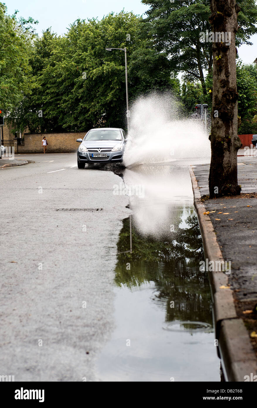A car drives through a puddle following a period of torrential rain. Stock Photo