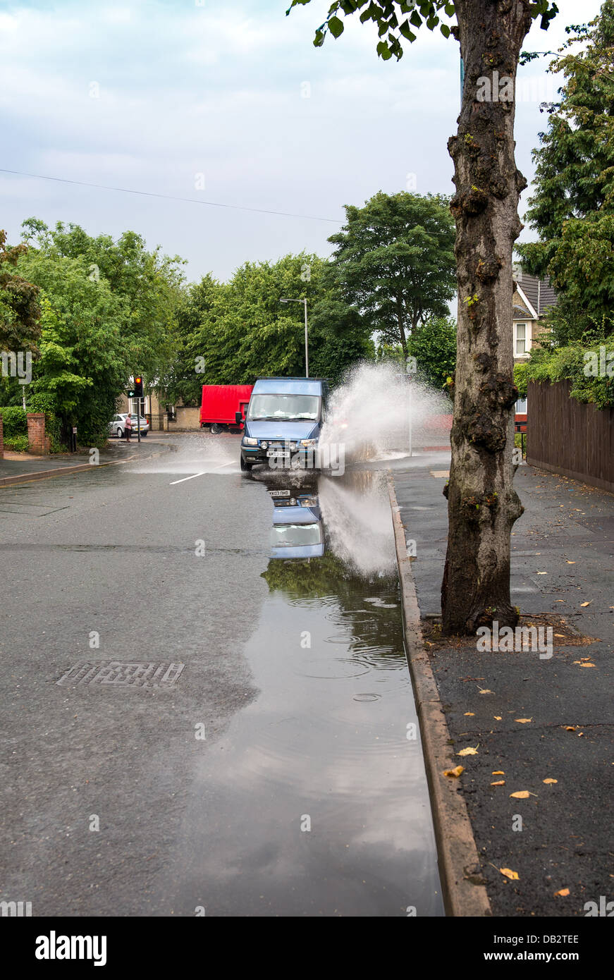 Van driving through puddle on side of road. Stock Photo