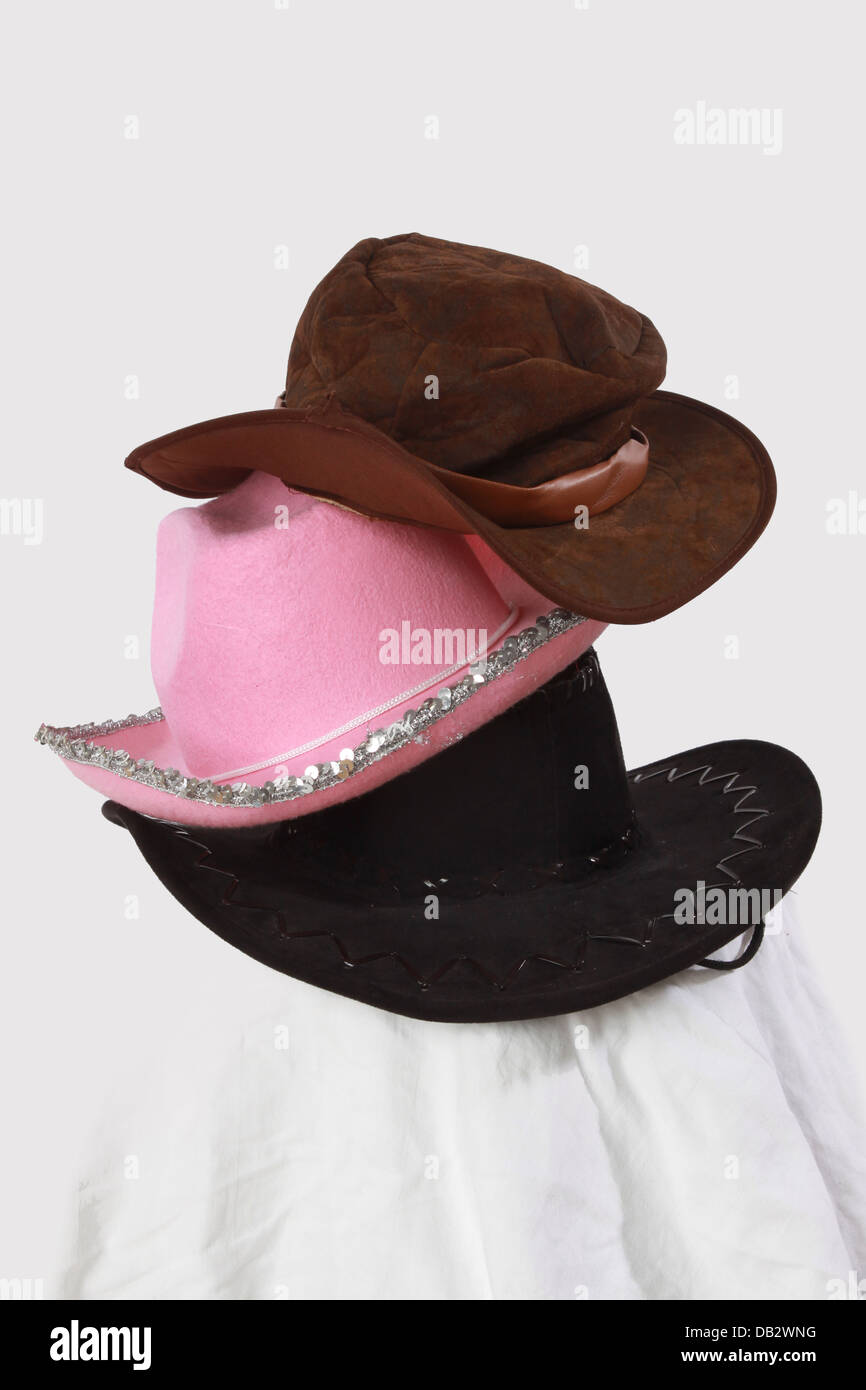 stack or pile of different rural hats. American stetson hat and australian outback hat. Also a pink cowboy hat with silver stars Stock Photo