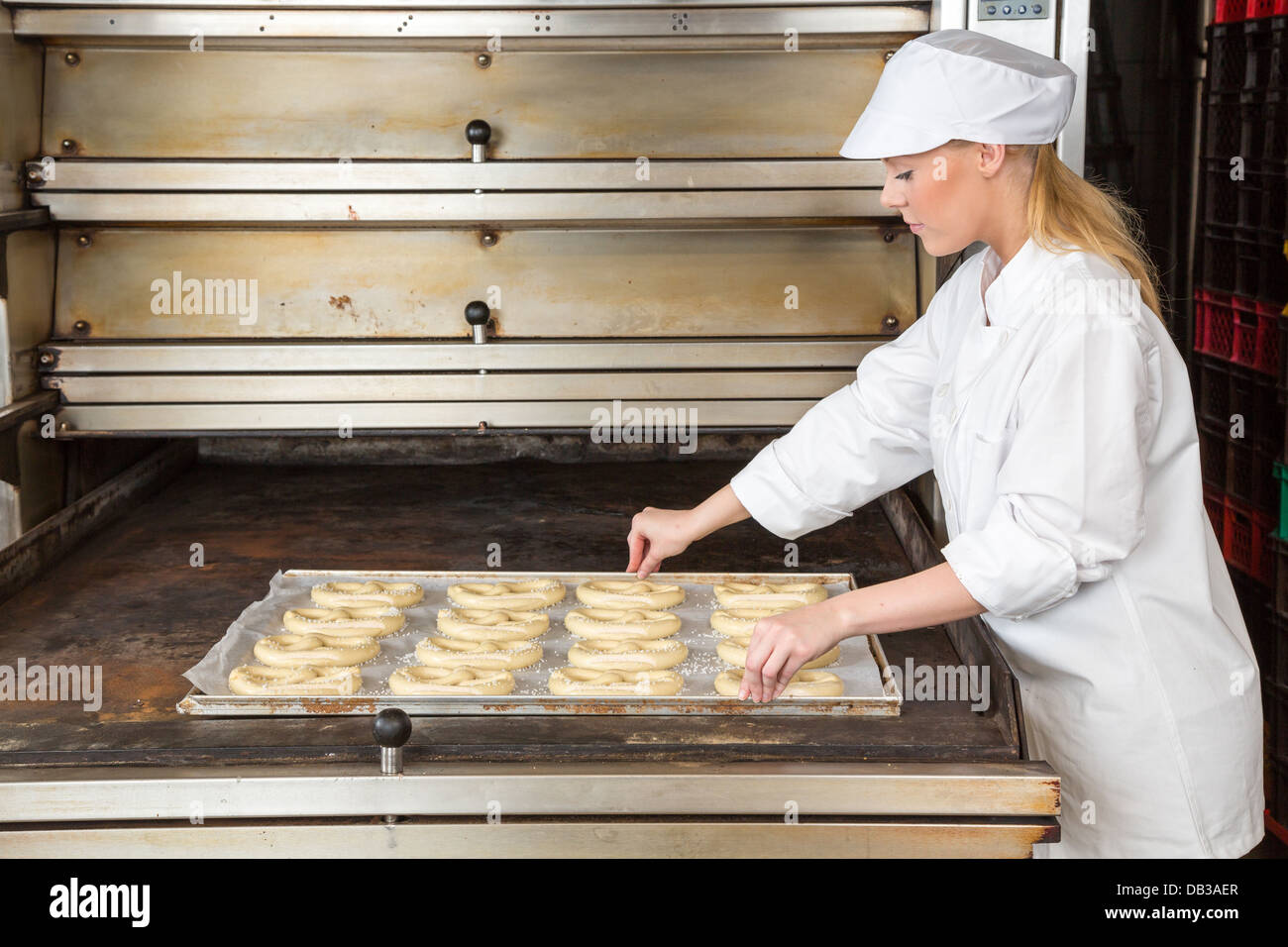 Baker in bakehouse or bakery presenting baking plate with pretzel dough Stock Photo