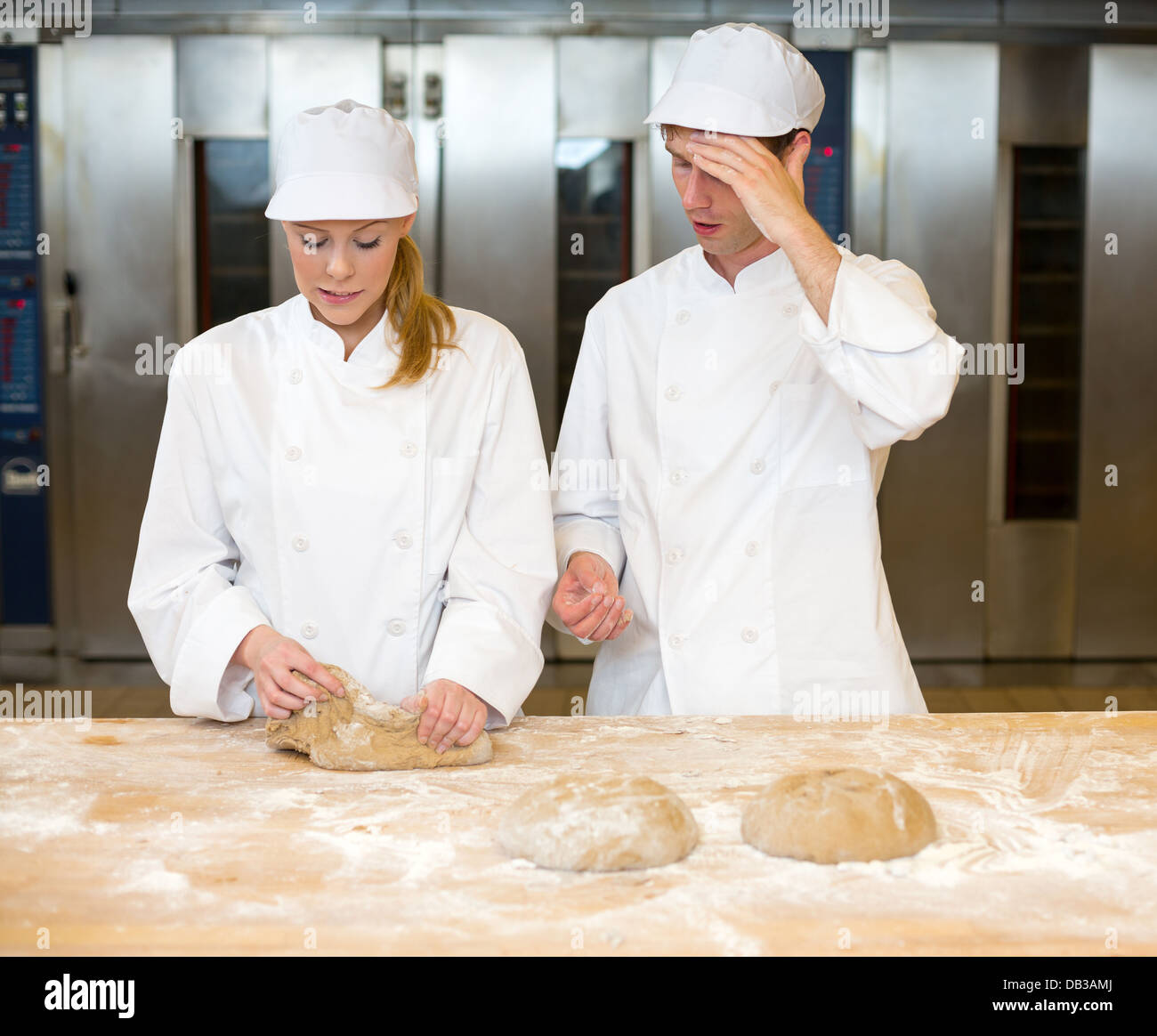 Instructor in bakery teaching baker apprentice how to knead dough Stock