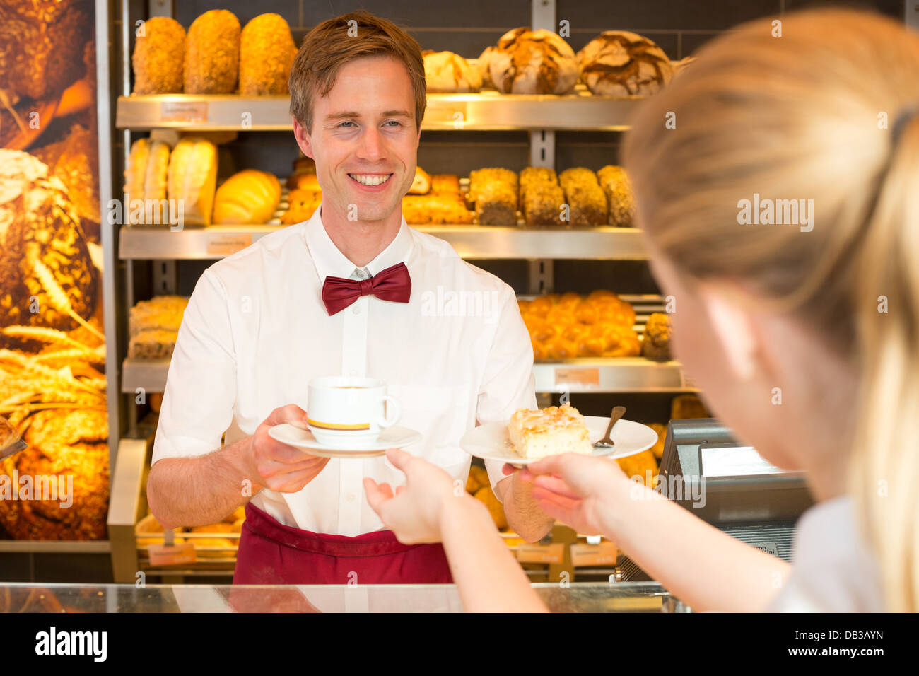 Shopkeeper in bakery giving cup of coffee or tea to customer Stock Photo