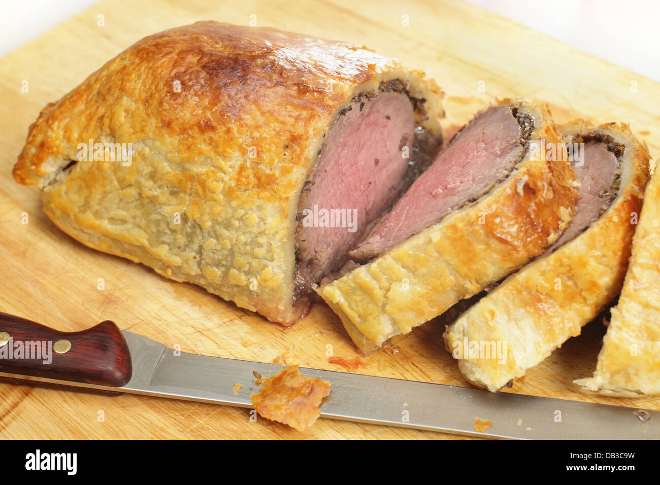 A beef wellington, or Boeuf en croute, sliced on a wooden chopping