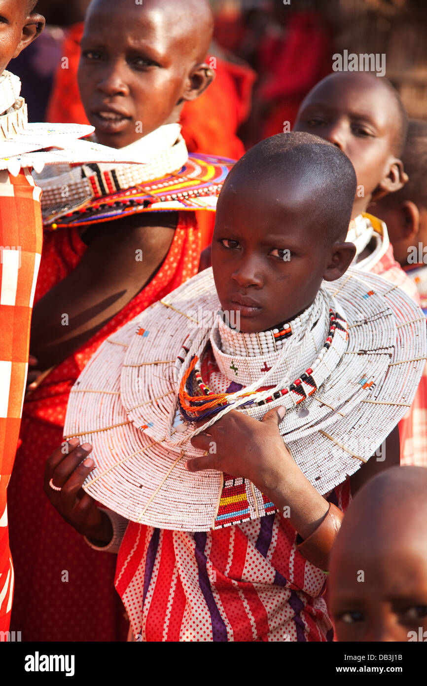 Young Maasai girls dressed up for a wedding party wearing traditional beads and red shukas and shaved heads. Stock Photo
