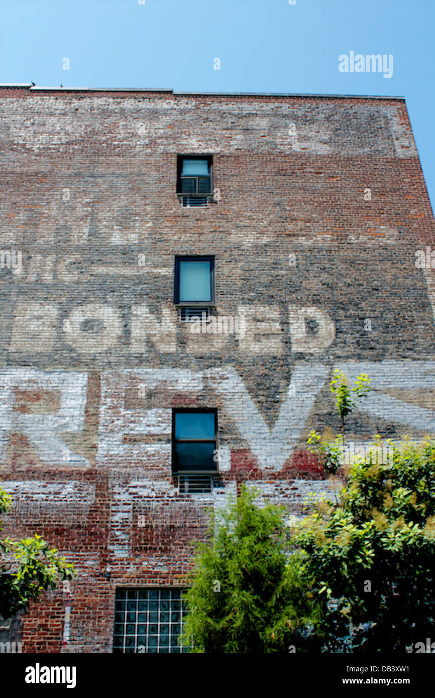 Painted advertisement on the side of a brick building. Stock Photo