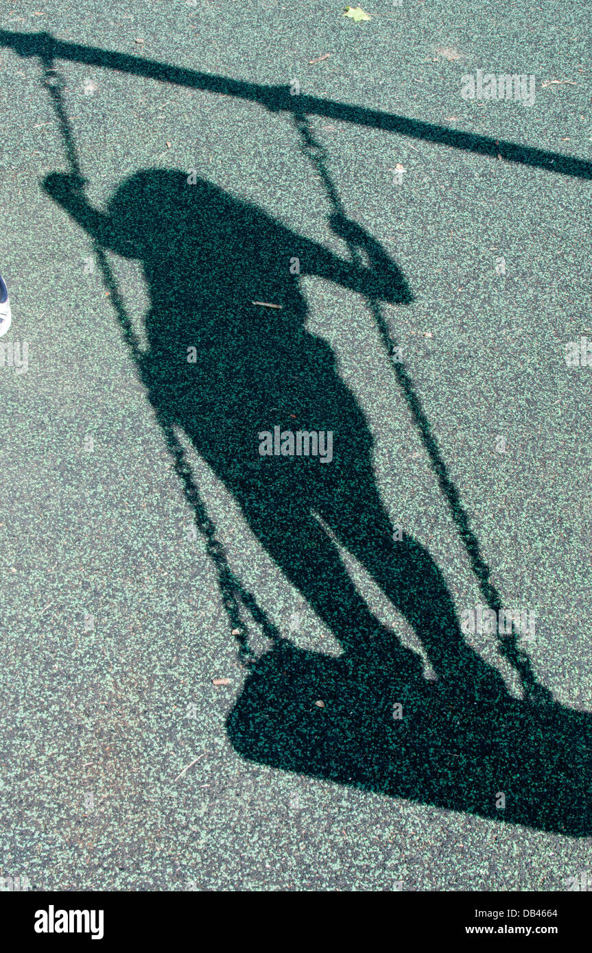 shadow of a girl standing on a swing Stock Photo
