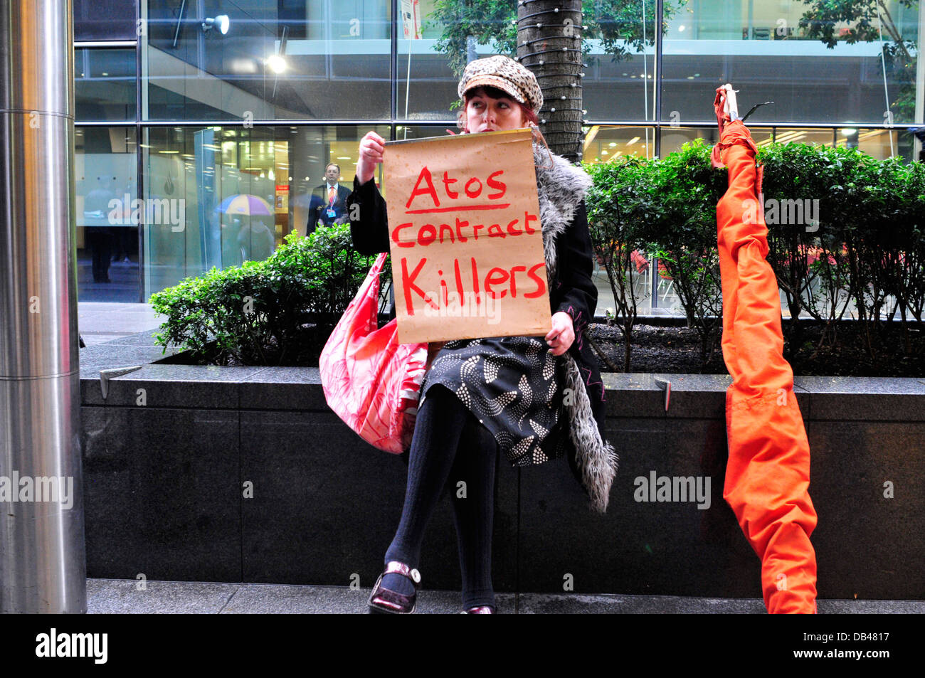 A woman holds a placard ' ATOS contract killers' London, United Kingdom Stock Photo