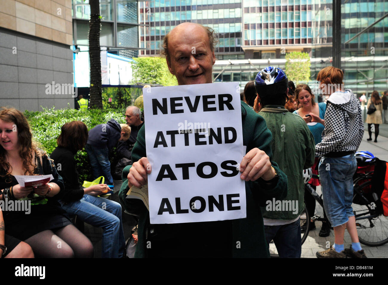 A man holds a placard reading  'Never attend ATOS alone' Triton Square, London, United Kingdom Stock Photo